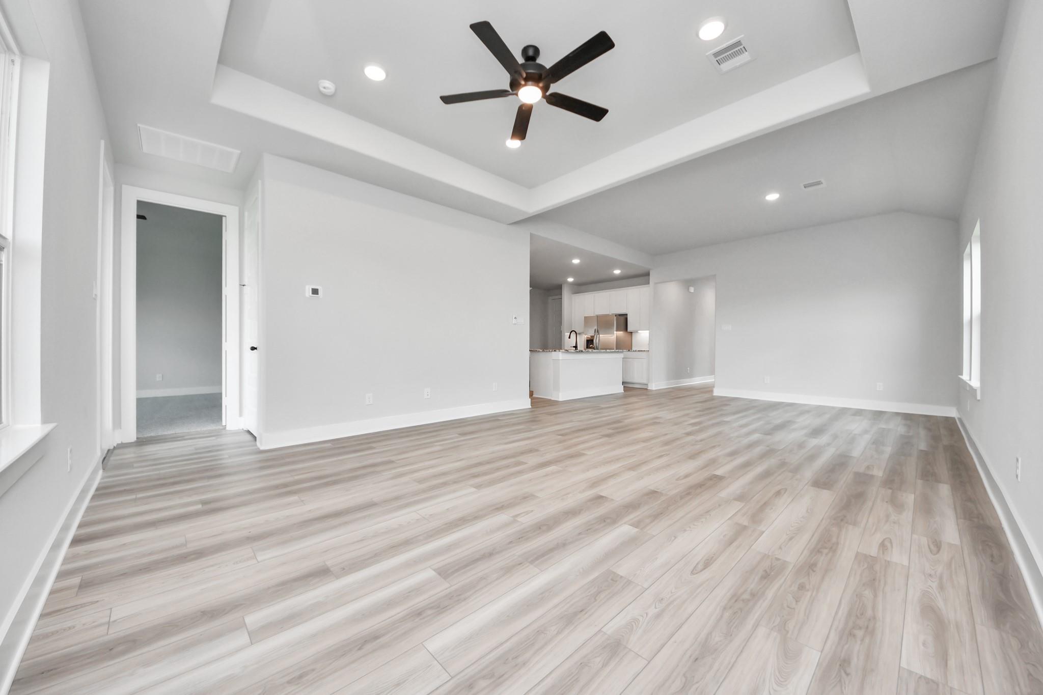 Spacious open-concept living room with tray ceiling in The Laguna C floor plan by Davidson Homes in Sunterra, Katy, Texas.