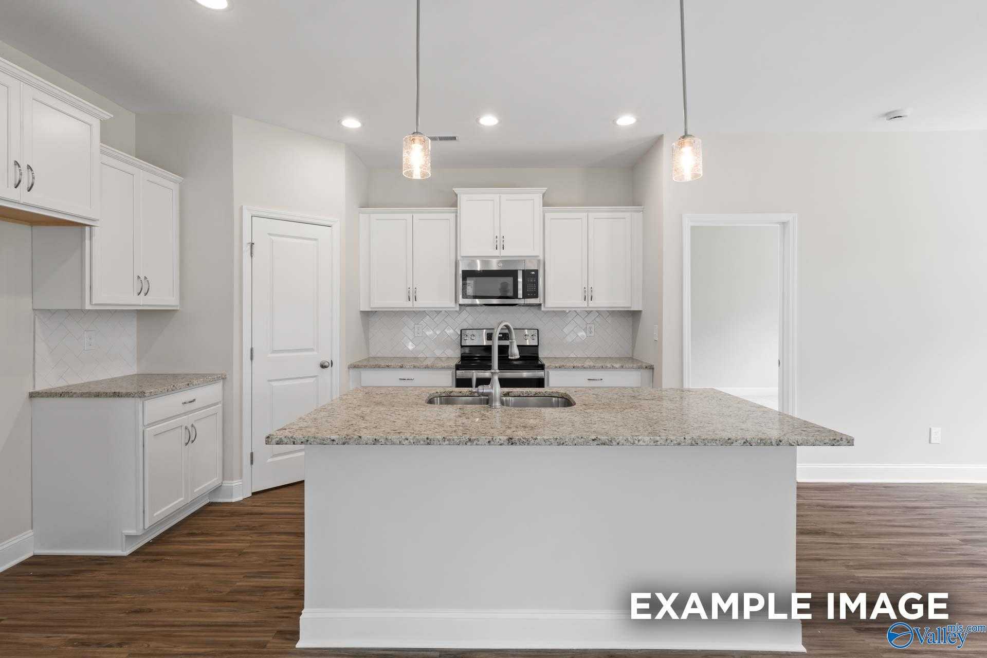 Modern kitchen with white cabinets, granite island, stainless appliances in The Franklin 3-bedroom home, New Market, Alabama