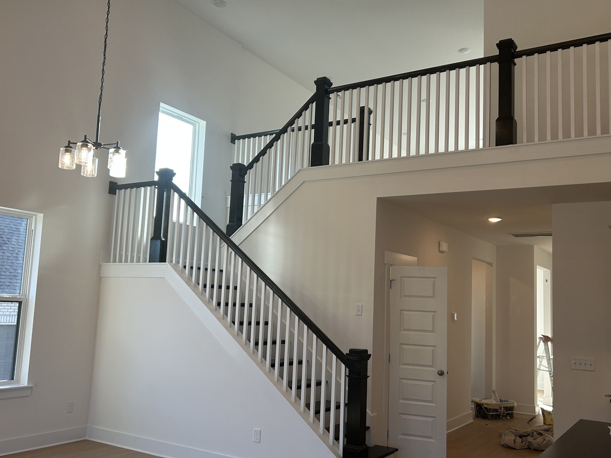 Grand two-story staircase with black railings, white balusters, and chandelier in Davidson Homes The Ridgeport E, Mt. Juliet, Tennessee