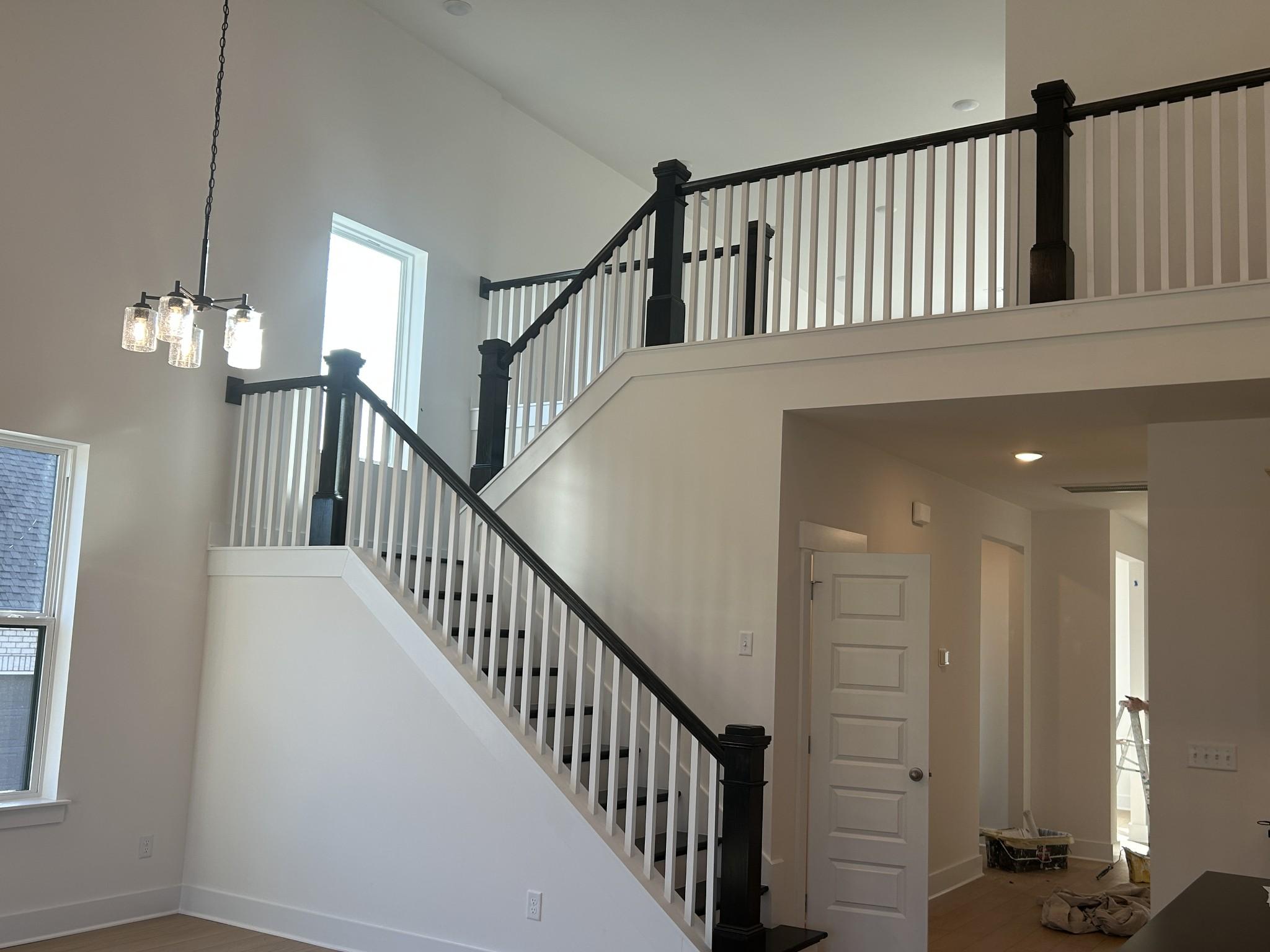 Grand two-story staircase with black railings, white balusters, and chandelier in Davidson Homes The Ridgeport E, Mt. Juliet, Tennessee
