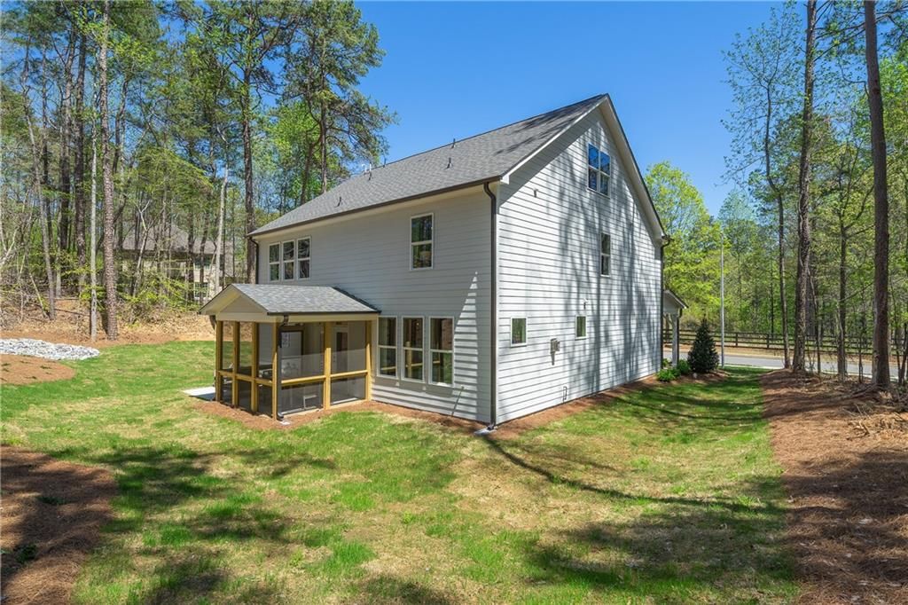 Two-story white Willow B home by Davidson Homes in Riverwood, Dallas, Georgia, featuring covered porch and wooded lot