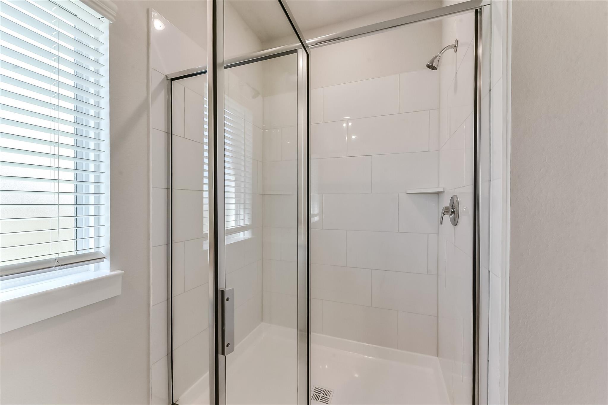 Modern glass-enclosed walk-in shower with white subway tiles in master bathroom, Davidson Homes The Costa C, Dayton Texas