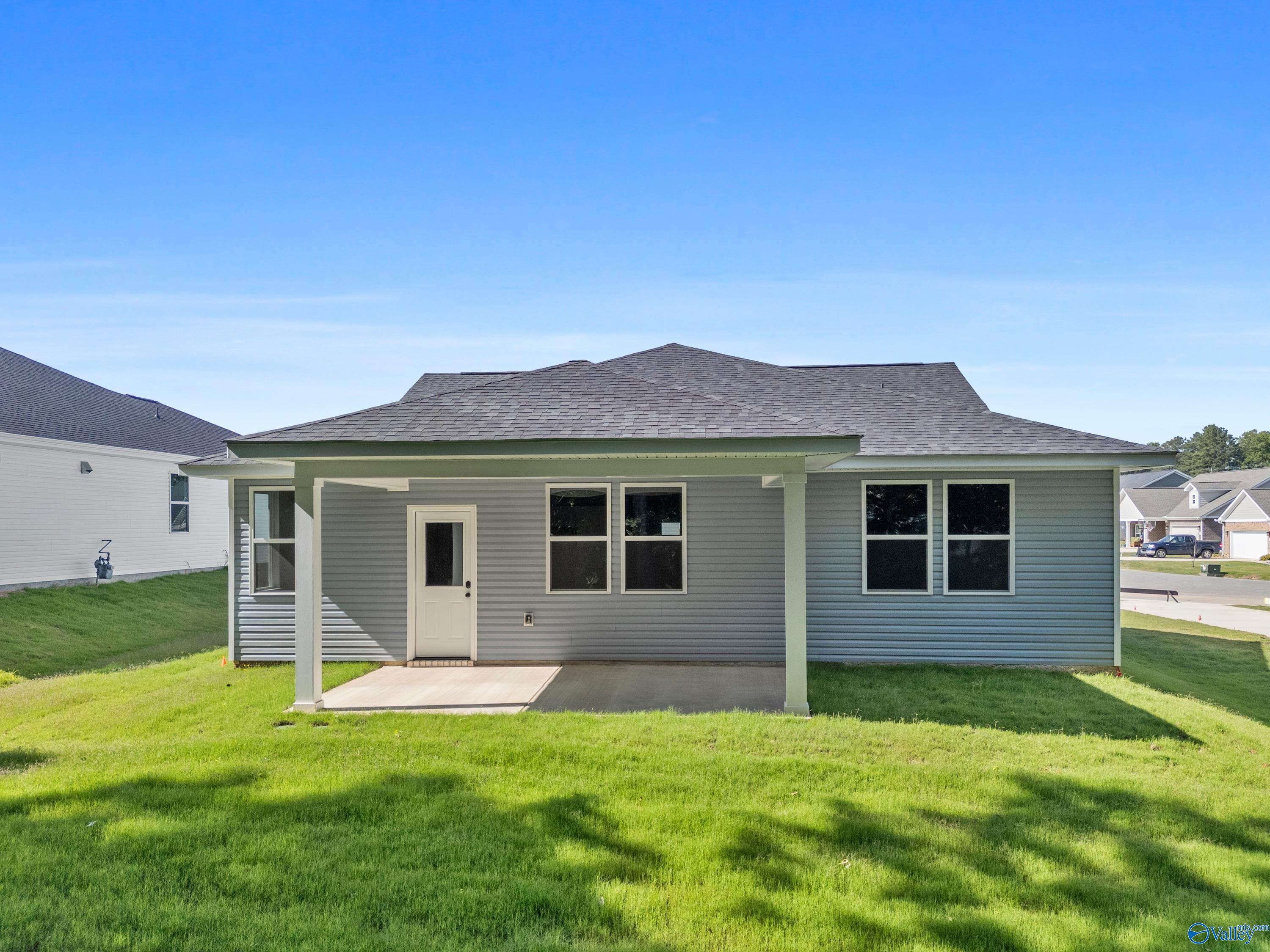 Rear view of The Phoenix 3-bedroom home by Davidson Homes with covered patio, gray siding and lush green lawn in Bailey Park, Fayetteville, TN