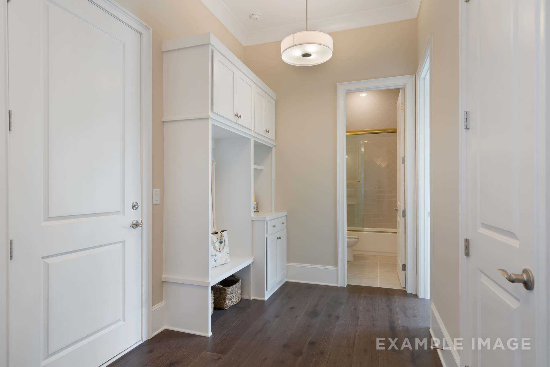 Spacious mudroom in The Seaside B home with white lockers, cabinets, adjacent powder room, and hardwood floors