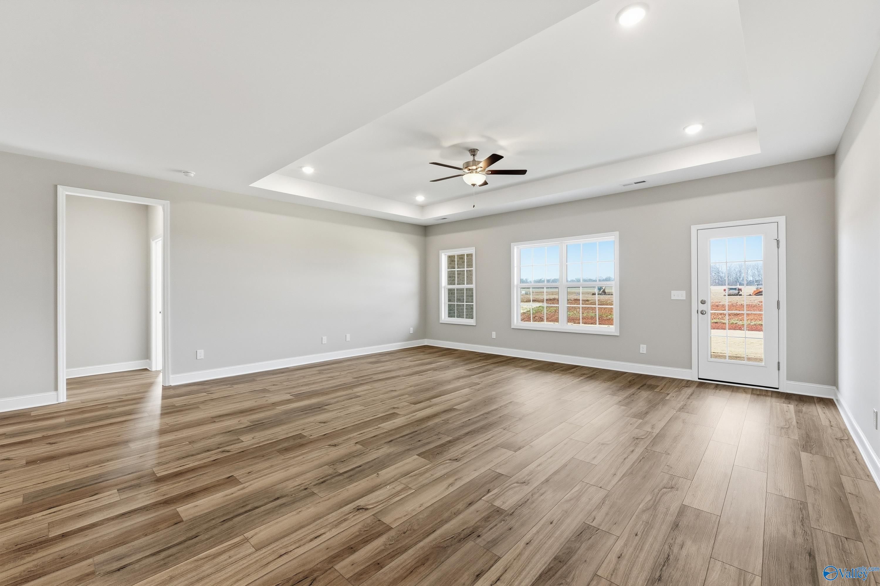 Spacious living room with hardwood floors, ceiling fan, large windows, and gray walls in The Lanier floor plan by Davidson Homes, Meridianville, AL
