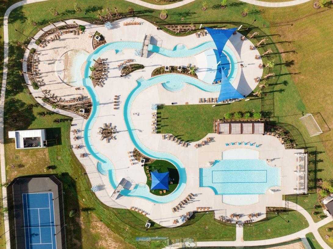 Aerial view of resort-style pool with lazy river, cabanas, and tennis courts in Sierra Vista, Rosharon, Texas