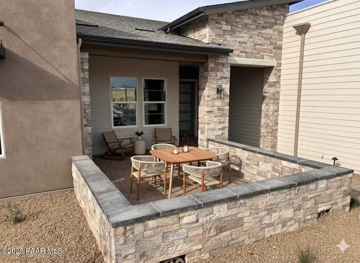 Covered patio with teak dining set, stone accents, and desert landscaping in Davidson Homes The Blaze D, Prescott Arizona