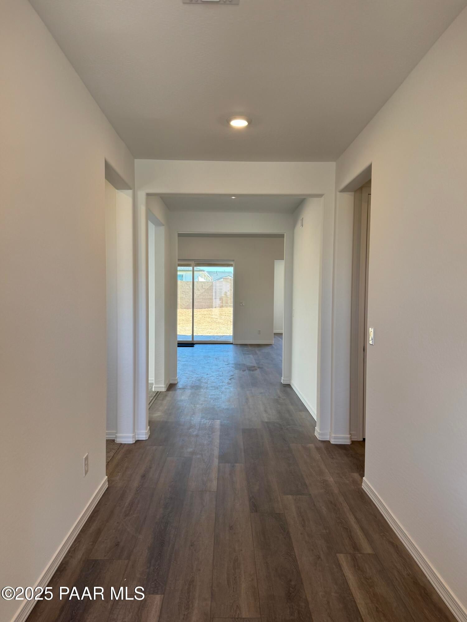 Spacious hallway with luxury vinyl plank floors, white walls, and sliding doors to backyard in Davidson Homes The Sunrise II A, Prescott, Arizona