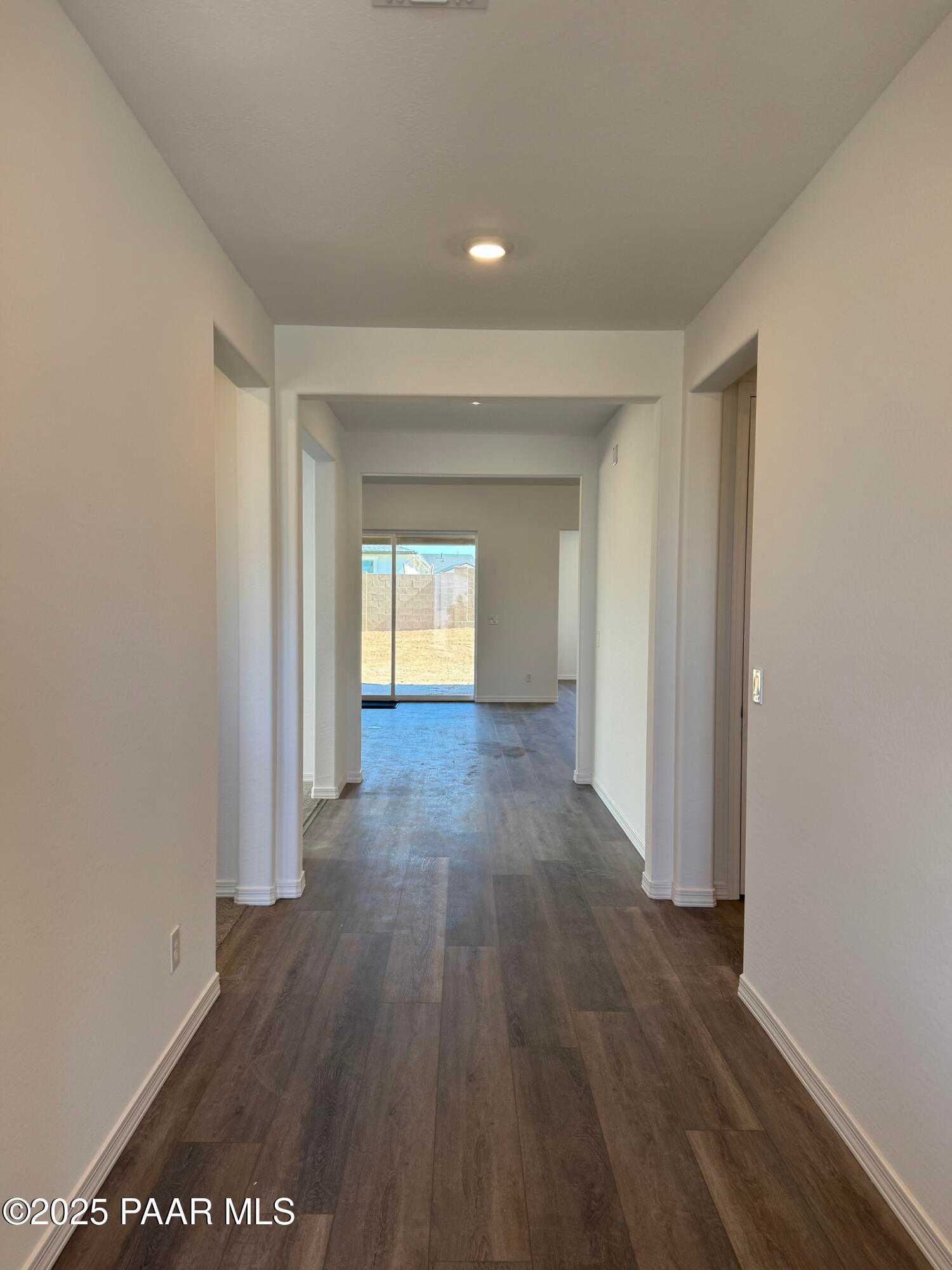 Spacious hallway with luxury vinyl plank floors, white walls, and sliding doors to backyard in Davidson Homes The Sunrise II A, Prescott, Arizona