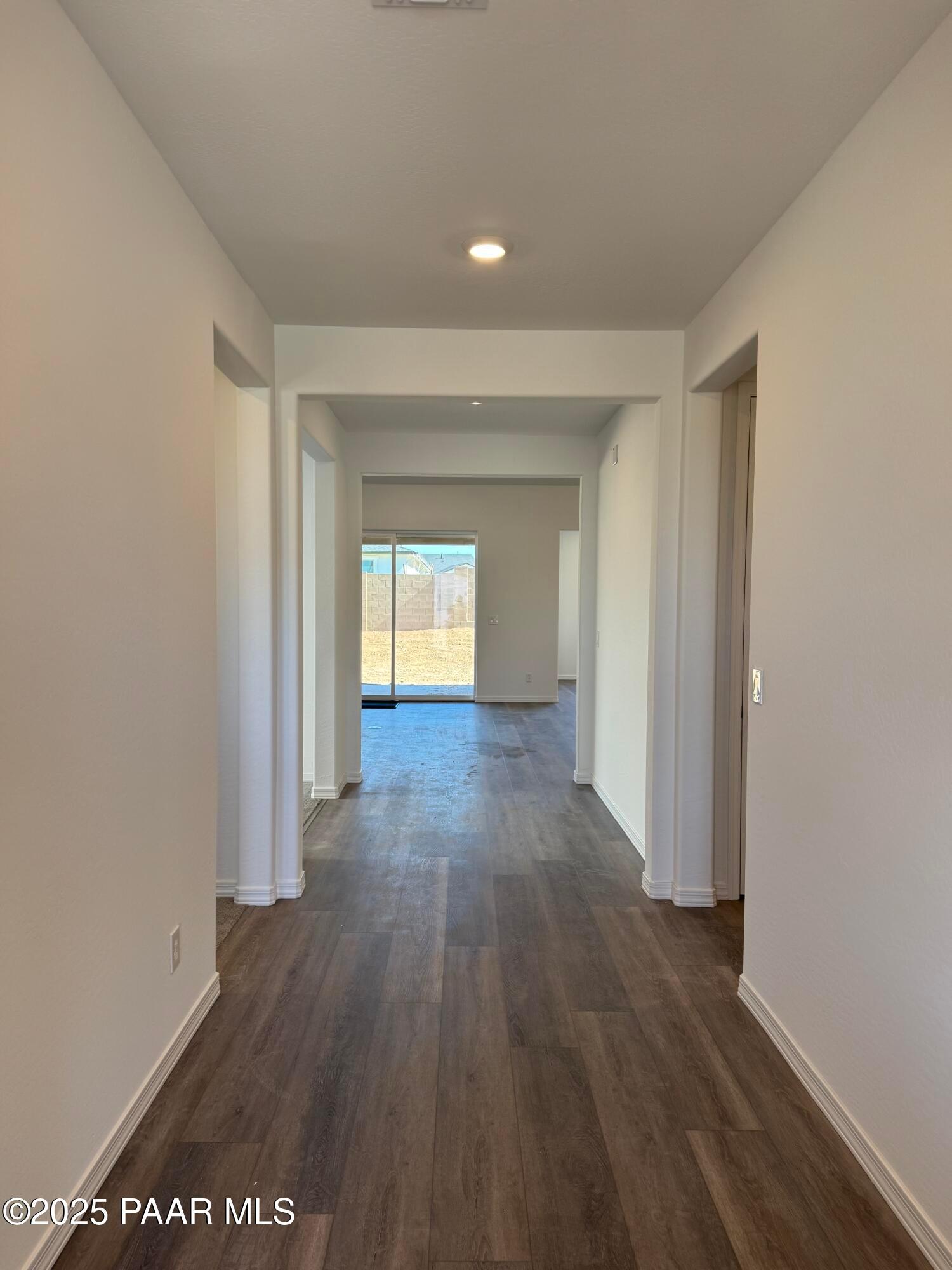 Spacious hallway with luxury vinyl plank floors, white walls, and sliding doors to backyard in Davidson Homes The Sunrise II A, Prescott, Arizona