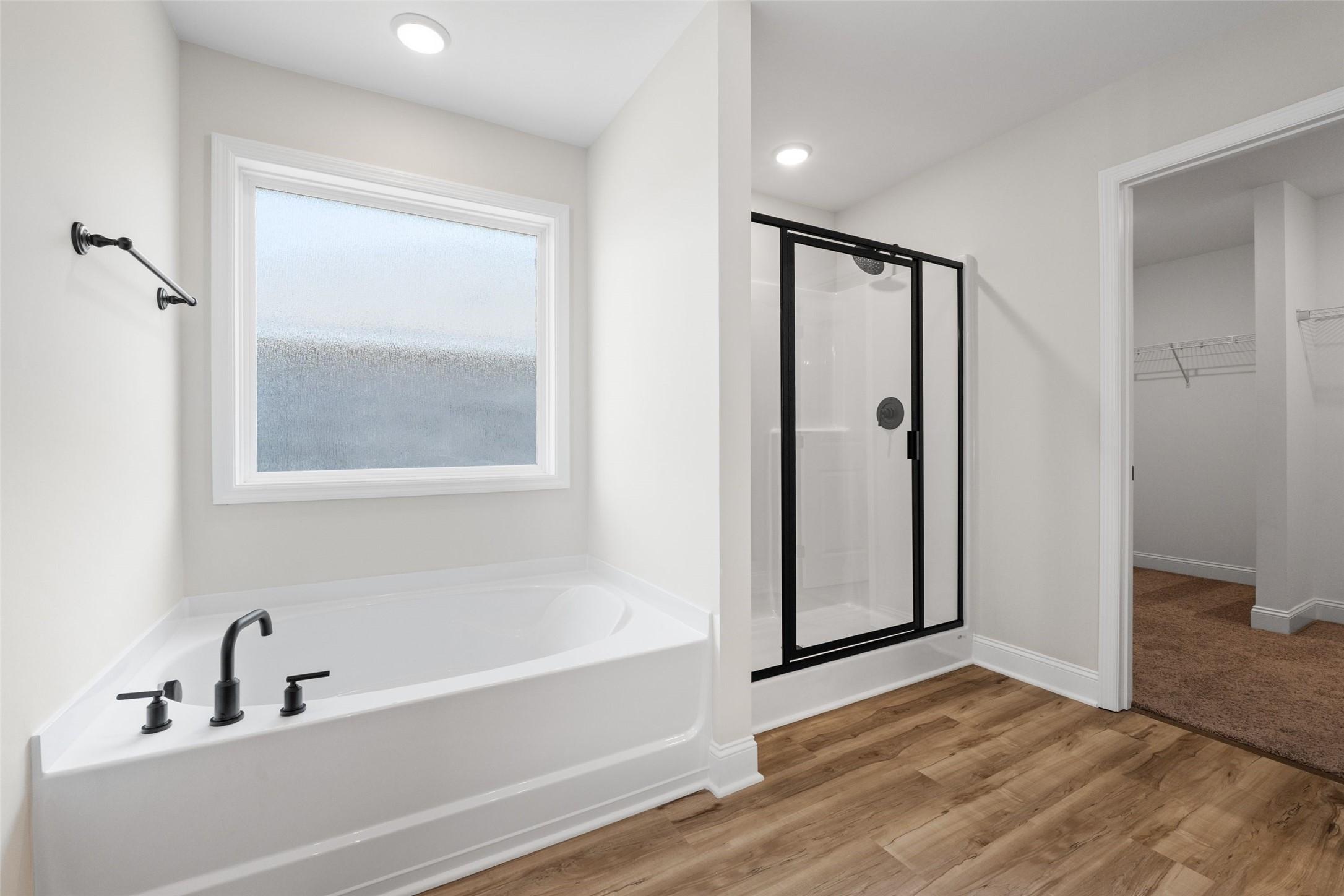 Primary bathroom with soaking tub, glass-enclosed shower, and walk-in closet in The Holly C plan, Parks at Foster Crossing.
