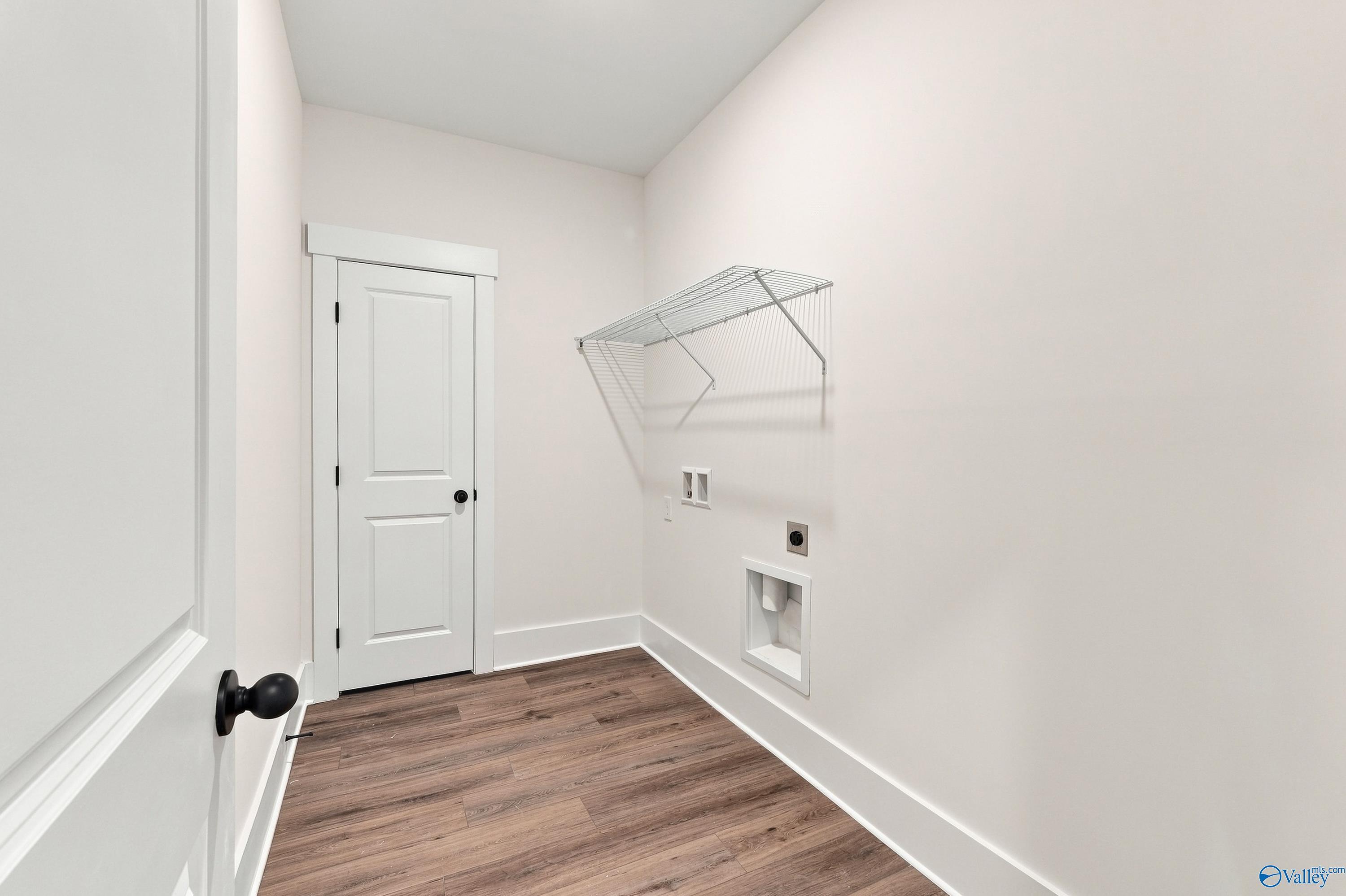 Laundry room with wire shelving, washer connections, and wood-look flooring in Davidson Homes Valencia, Riverton Preserve, Huntsville