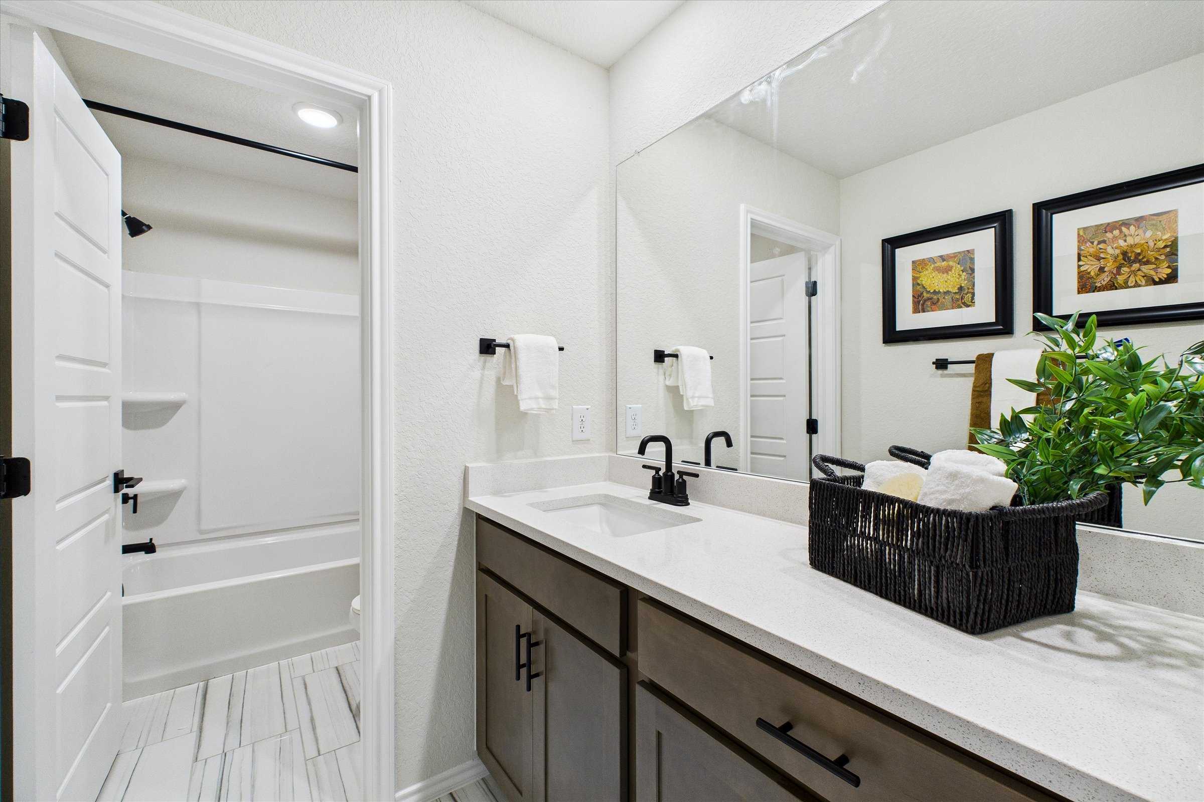 Contemporary bathroom with double vanity, quartz countertop, and open tub at Meadows at Oak Creek in San Antonio TX