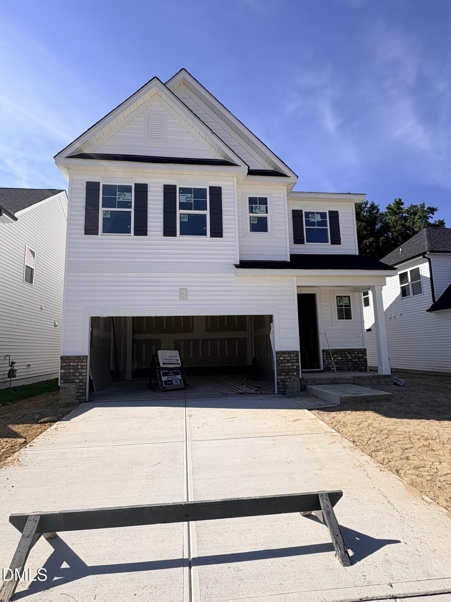 White two-story new construction home with black shutters and 2-car garage at Woodland Crossing, Zebulon NC by Davidson Homes