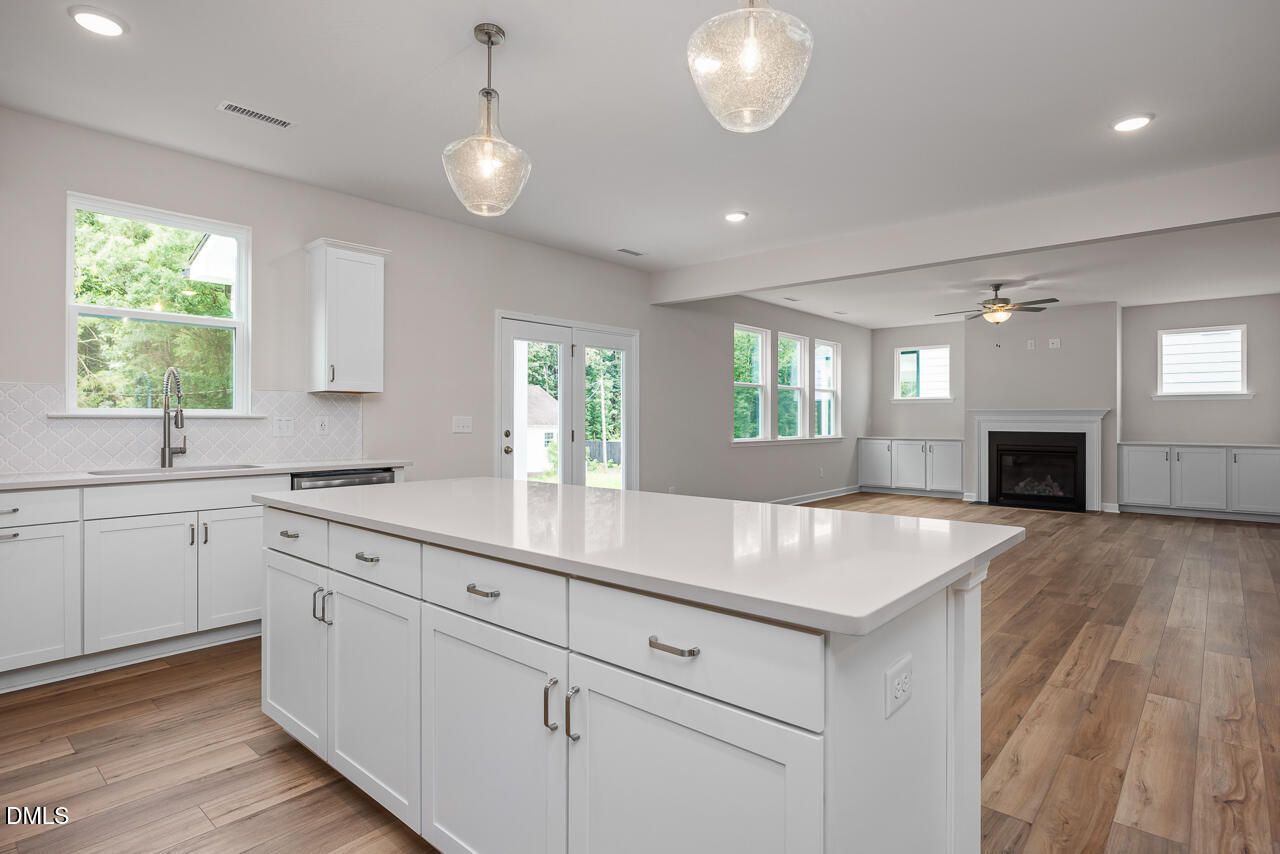 Open-concept kitchen with white quartz island and fireplace in The Hickory II C floor plan at Montrose, Aberdeen, NC.