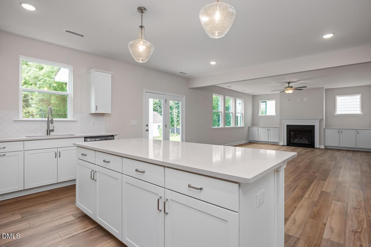 Open-concept kitchen with white quartz island and fireplace in The Hickory II C floor plan at Montrose, Aberdeen, NC.