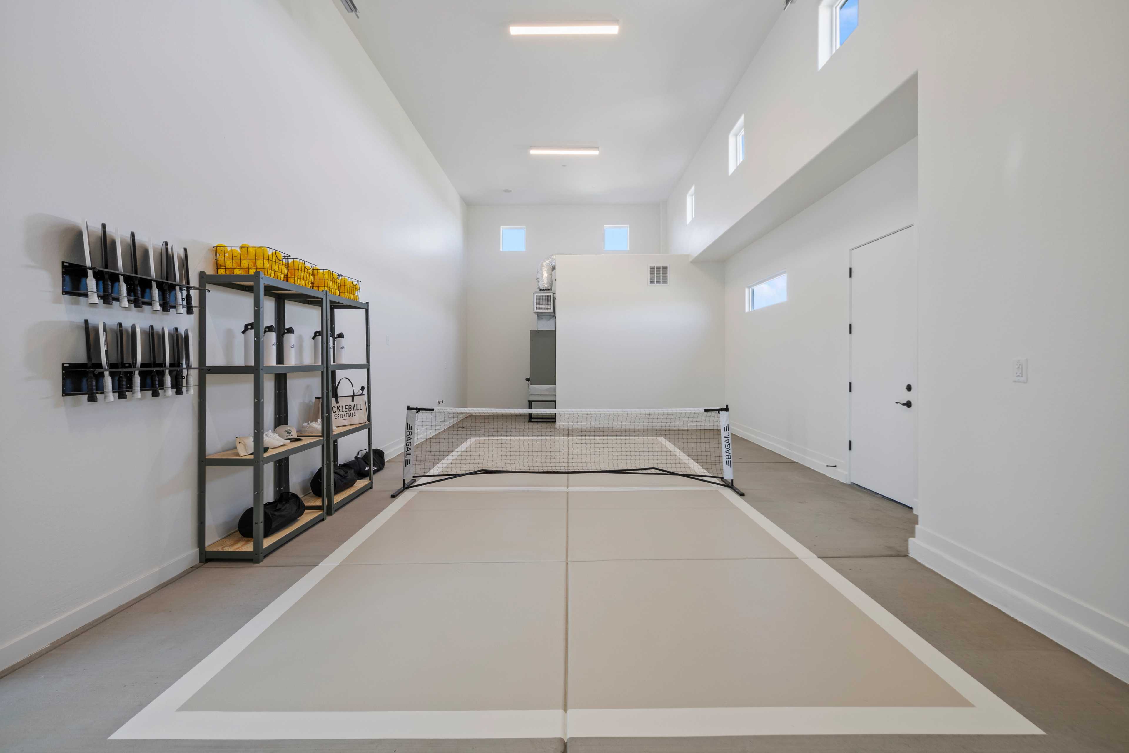Indoor pickleball court in Hidden Hills garage by Davidson Homes Prescott AZ with net, storage shelves, and marked flooring
