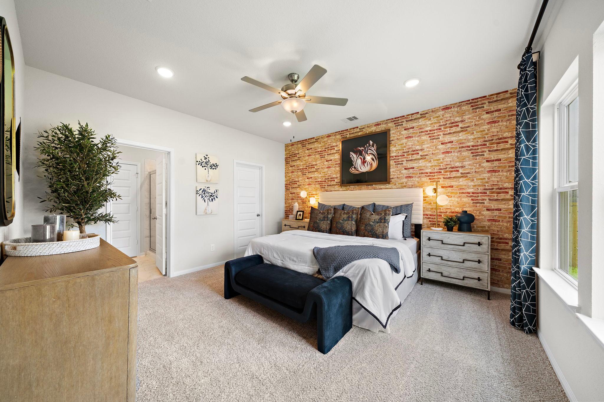 Master bedroom at Liberty Estates in Cleveland Texas with brick accent wall king bed ceiling fan and plush carpeting