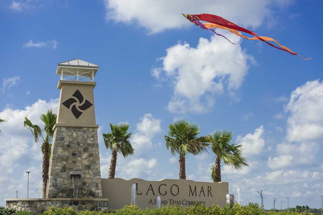 Lago Mar community entrance in Texas City Texas with stone tower palm trees and flying kite under blue sky