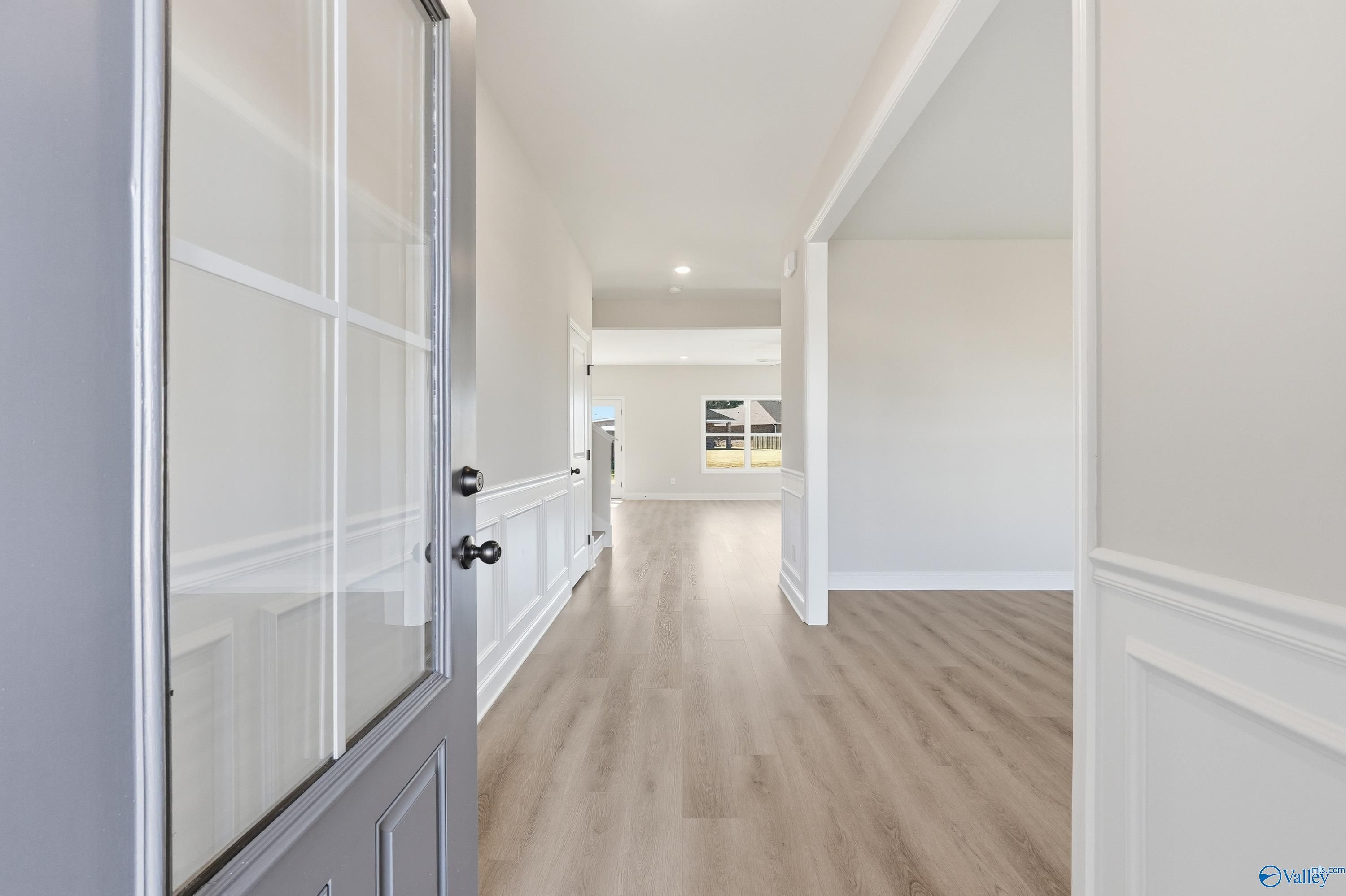Bright entry foyer with glass-paneled gray door, white trim, and oak hardwood floors in Davidson Homes Chelsea C, Harvest AL