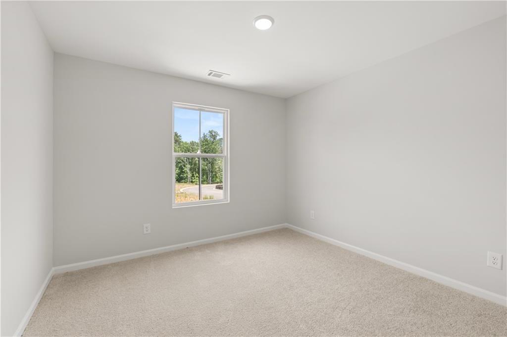 Bright, spacious secondary bedroom with neutral carpet in The Burton A floor plan at The Bluffs in Canton, Georgia.
