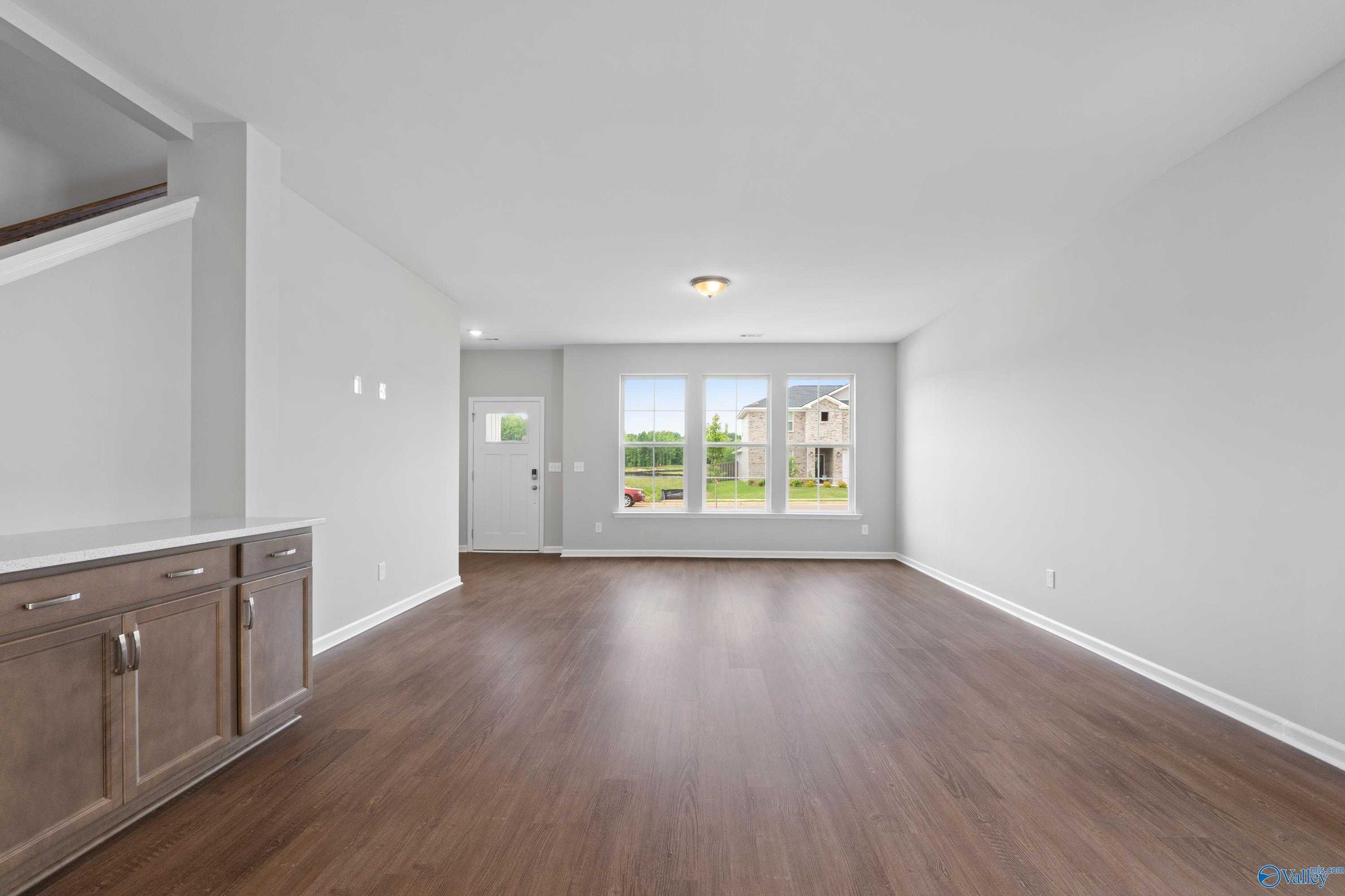 Bright entryway with hardwood floors, staircase, and large windows overlooking yard in Davidson Homes The Stella, Hazel Green, Alabama