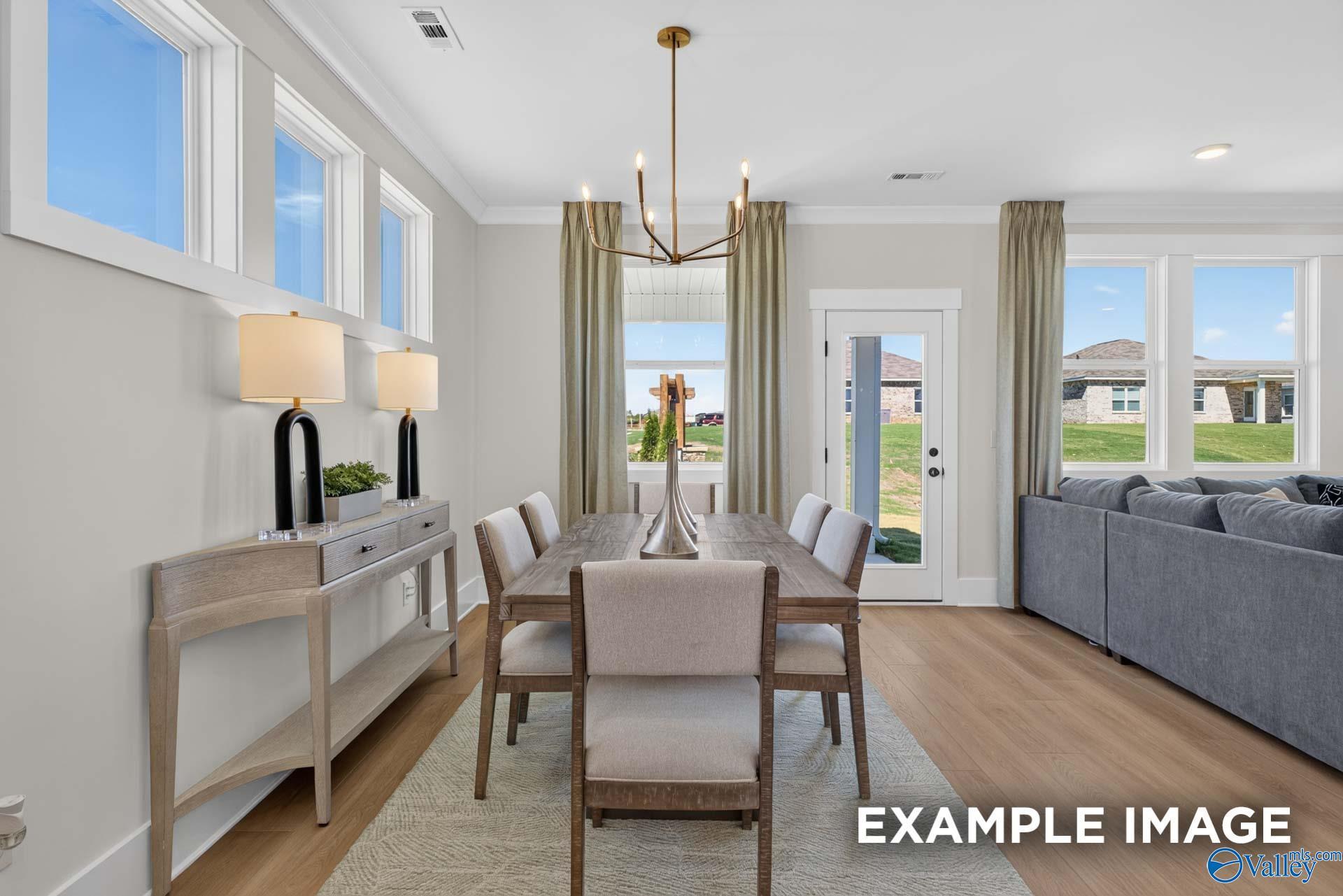 Bright dining area with wood table, brass chandelier, and open living room in Davidson Homes Ashport K, Hazel Green, Alabama