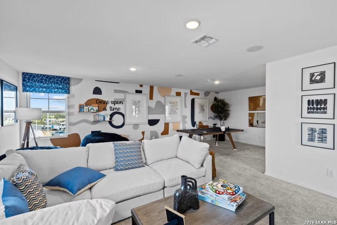 Modern living room with white sectional sofa, blue pillows, abstract art walls and wooden coffee table in Davidson Homes Douglas C, Converse, Texas