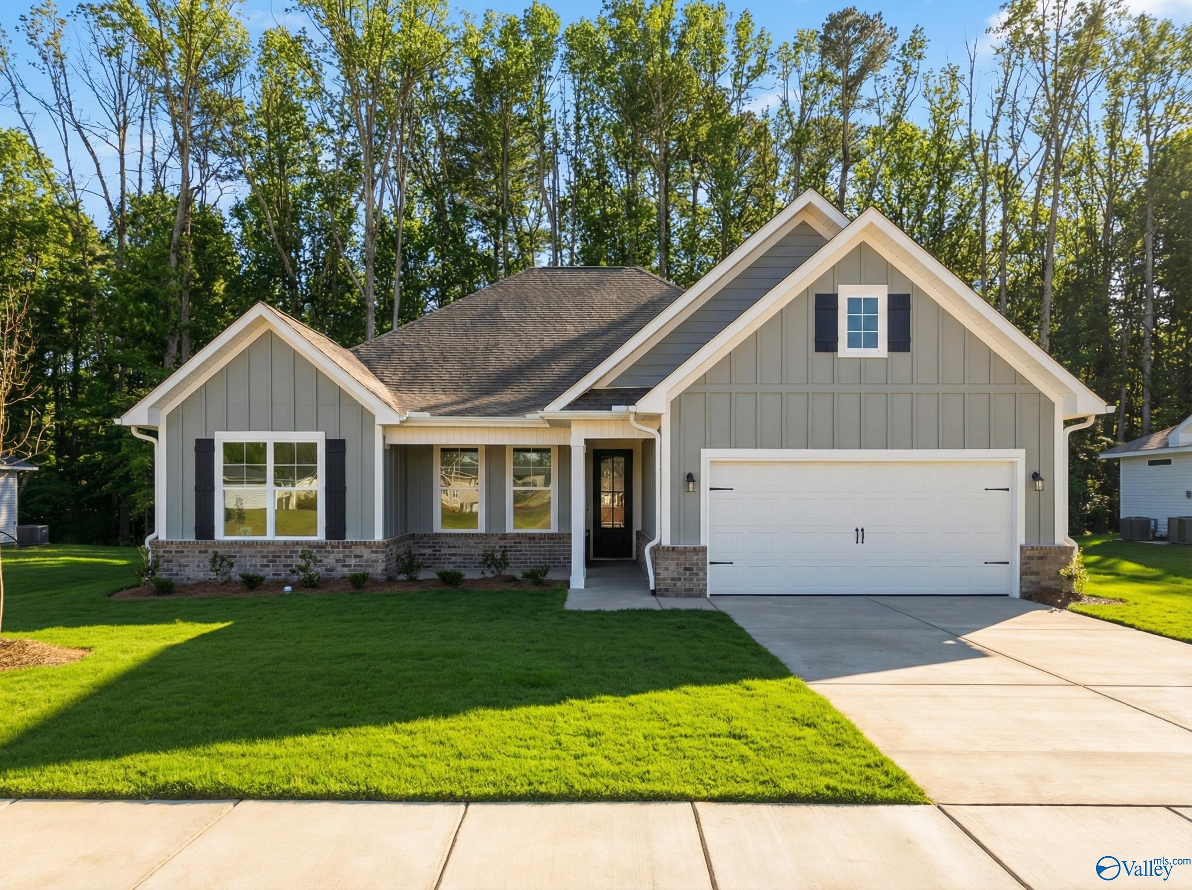 Modern gray single-story home with 2-car garage, brick accents, and lush landscaping in Forest Glen, Hazel Green, Alabama by Davidson Homes The Rockford D