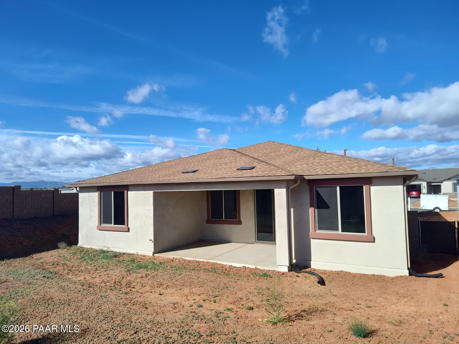 Beige single-story home with covered patio, large windows, and desert backyard in North Ridge at Pronghorn Ranch, Prescott Valley