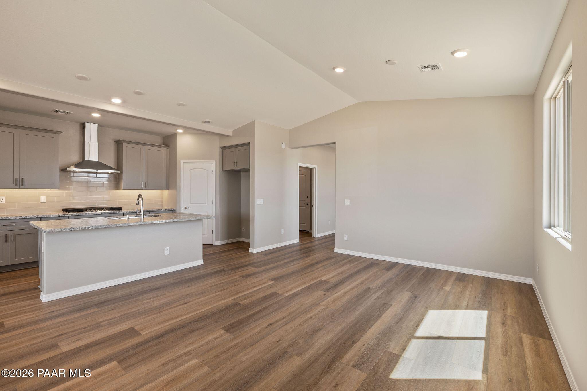 Open kitchen with gray cabinets, stainless steel appliances, and wood floors in Davidson Homes The Frontier A, Prescott Valley AZ