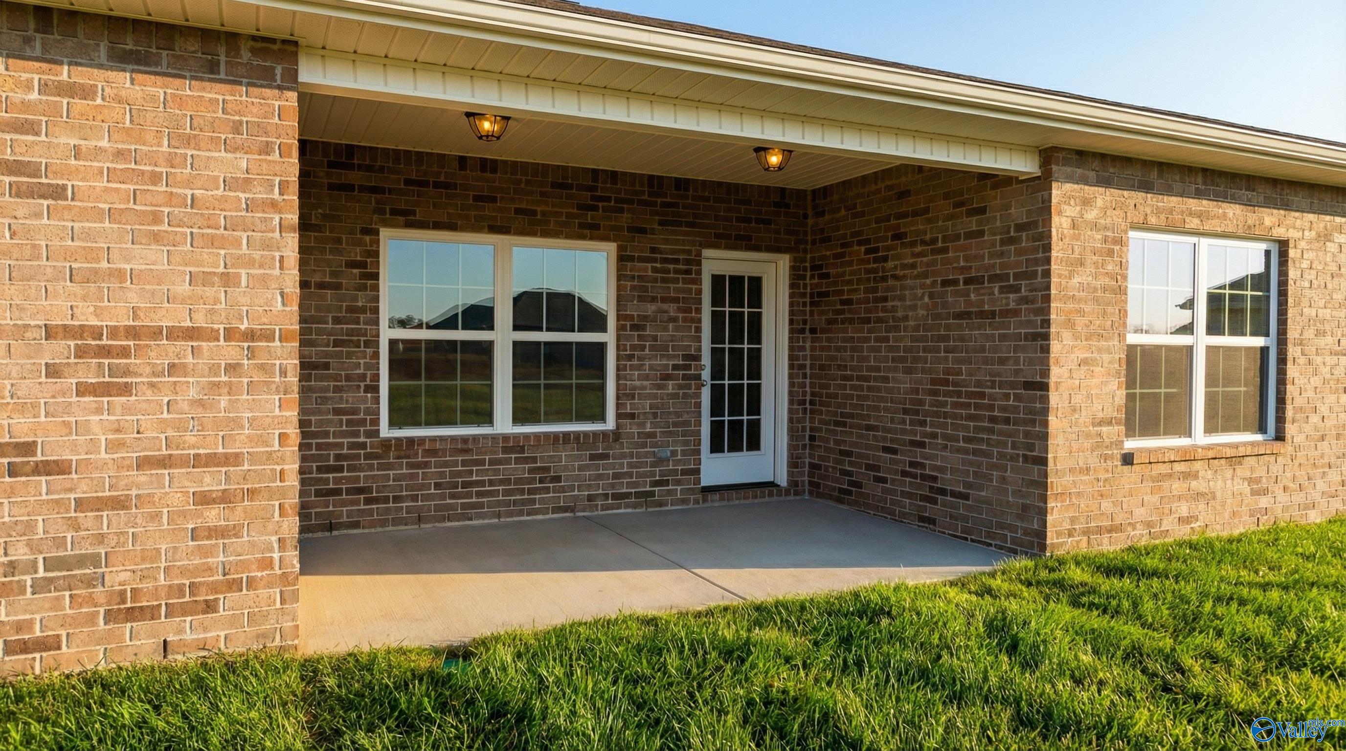 Covered brick patio with large windows and French door overlooking lush lawn in Davidson Homes Montgomery C, Harvest AL