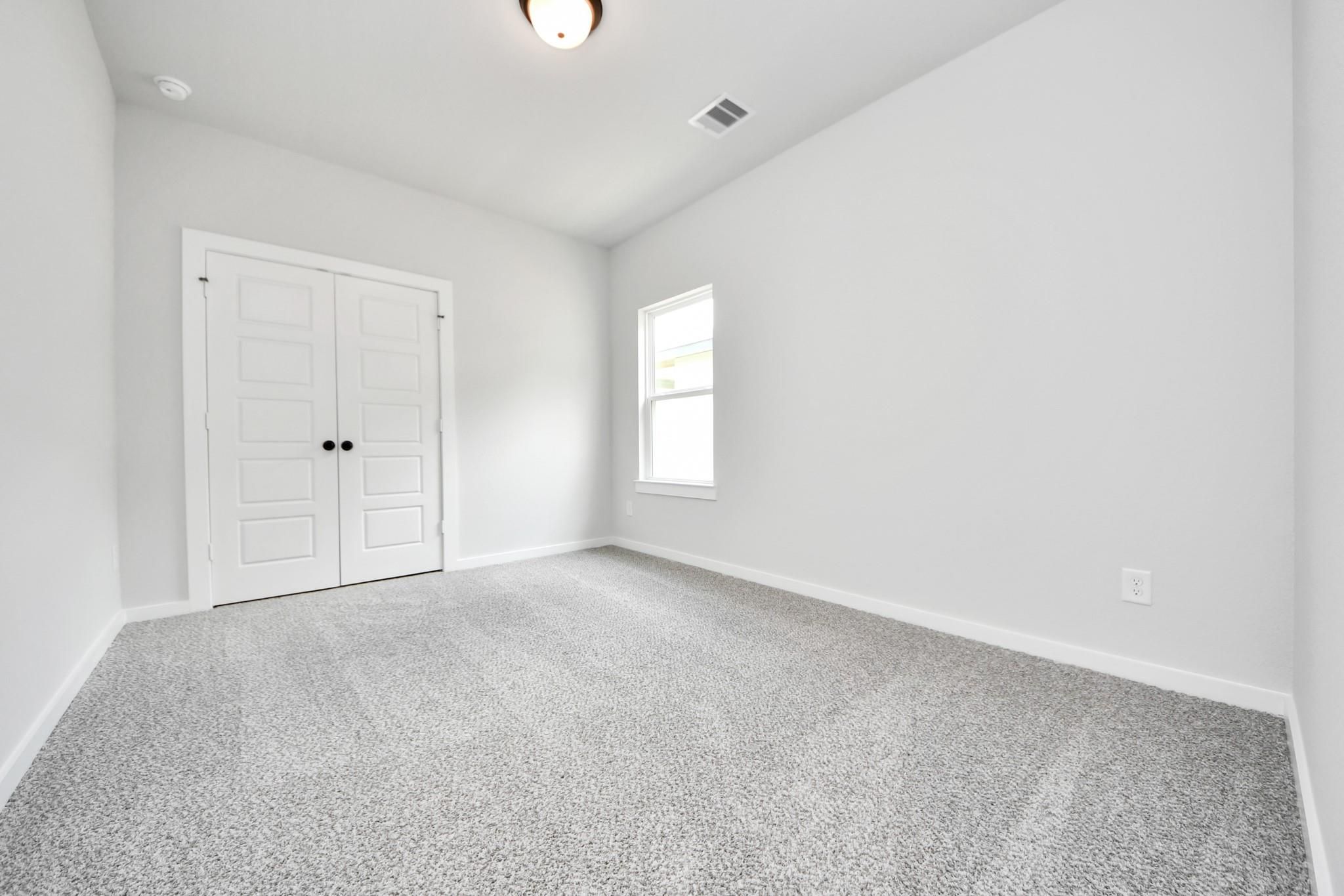 Bright bedroom with plush carpet and closet in The Sorrento E floor plan by Davidson Homes in Sundance Cove, Crosby, Texas.
