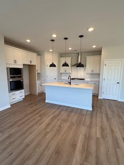 Modern white kitchen island with stainless double ovens, pendant lights, and hardwood floors in Davidson Homes The Durham B, Cumming, GA