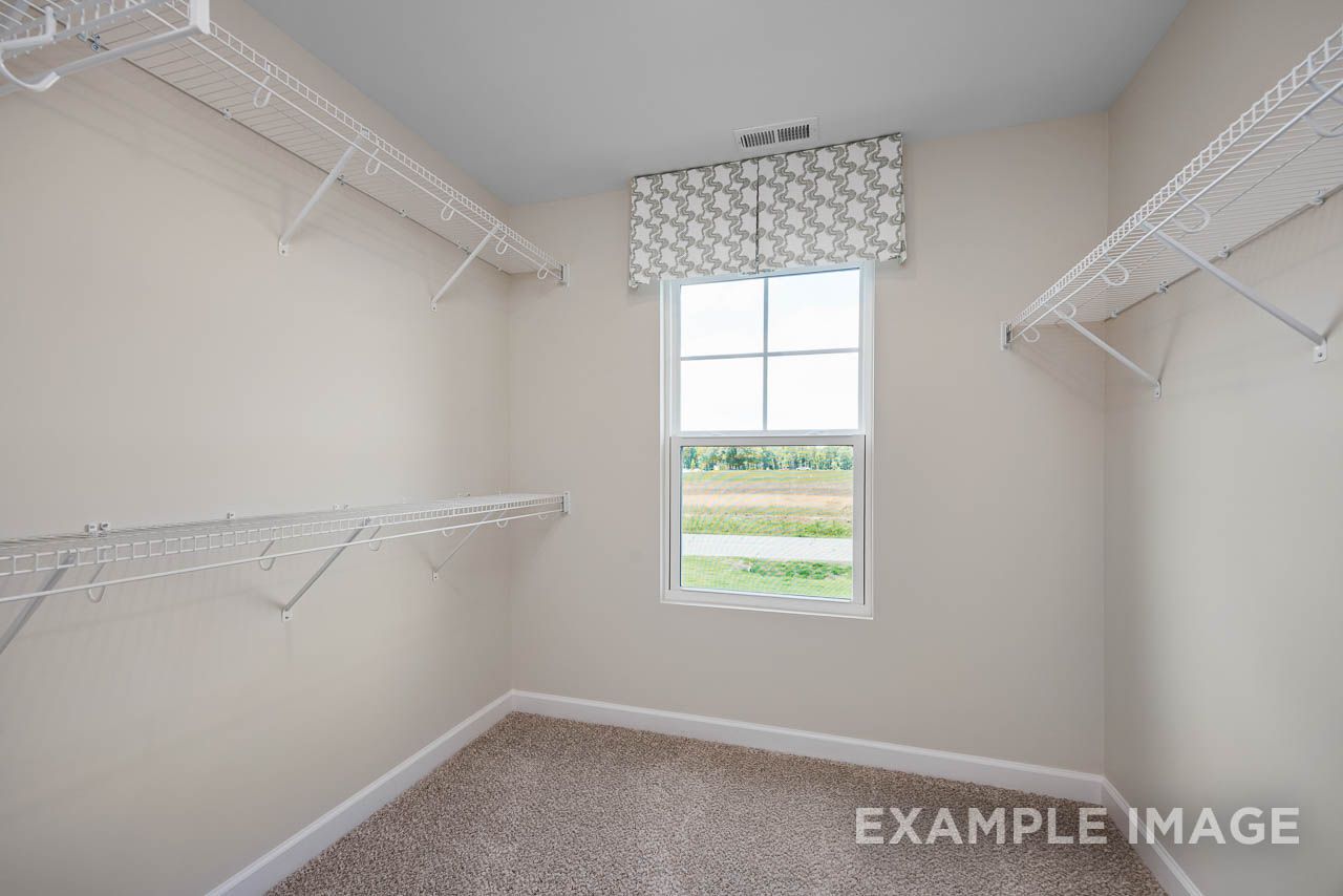Spacious walk-in closet with wire shelving and natural light in the master suite of The Willow C-BF by Davidson Homes.