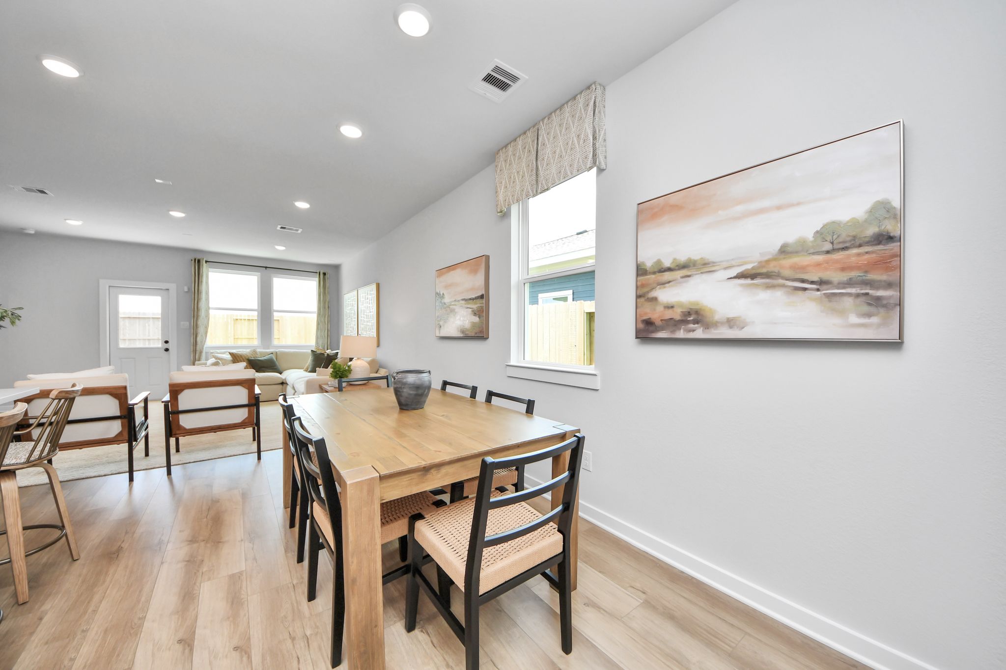 Open-concept dining and living area at Robins Landing in Houston, TX by Davidson Homes with wood floors and modern decor.