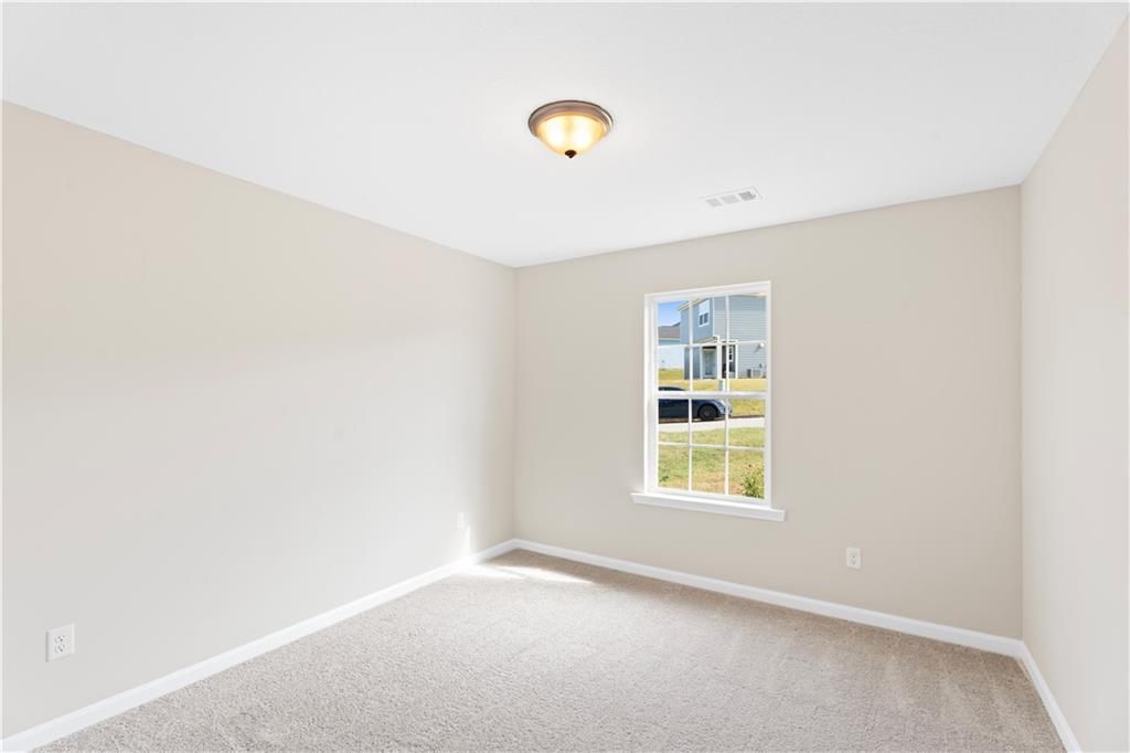 Bright secondary bedroom with beige walls, carpet floor, and window view in Davidson Homes The Washington, Phenix City