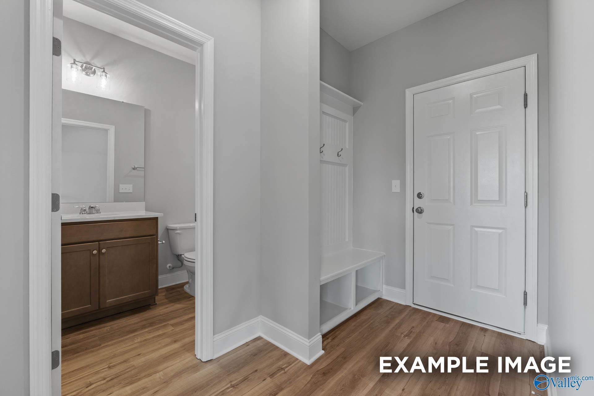 Mudroom with coat hooks, bench, and adjacent powder room in Davidson Homes The Shelby B, New Market, Alabama
