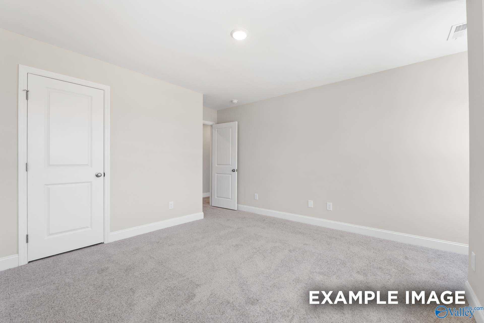 Spacious secondary bedroom with neutral beige walls, white doors, and plush carpet in Davidson Homes The Camden C, Huntsville AL