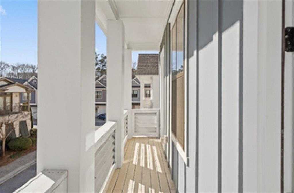 Expansive second-story balcony with white columns and wood deck overlooking neighborhood homes in Davidson Homes The Seaside A, Woodstock, GA