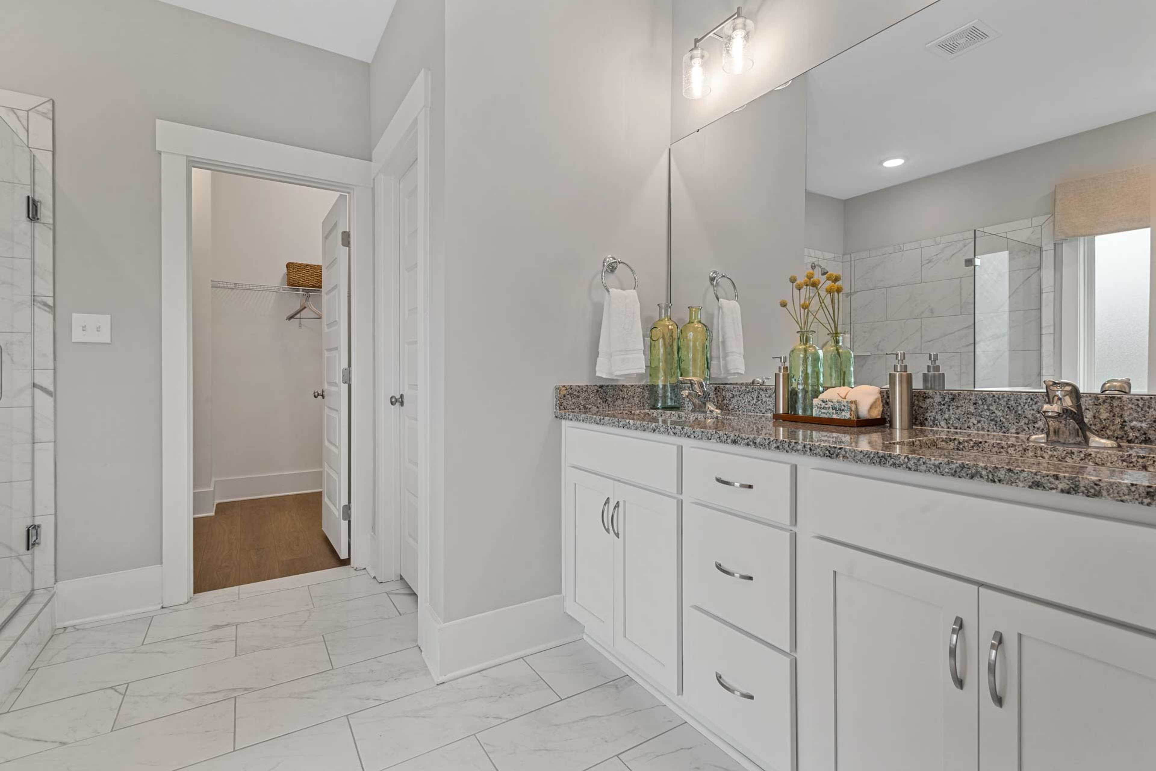 Spacious primary bathroom at Monteagle Cove in Owens Cross Roads AL with double vanity, granite counters, subway tile shower, and walk-in closet