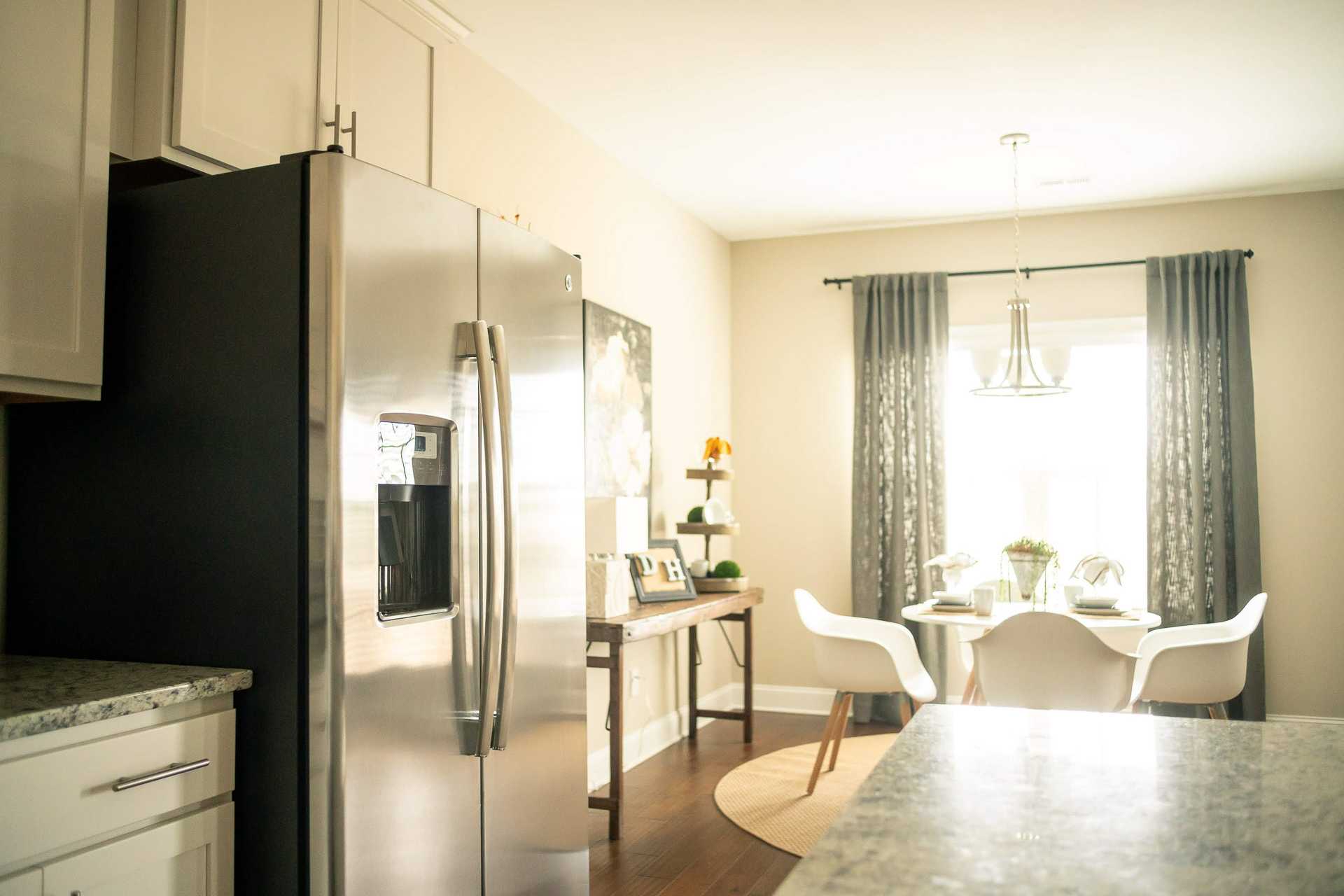 Modern open-concept kitchen and dining area at Summer Pointe in Madison, Alabama with stainless steel fridge, granite counters, and hardwood floors