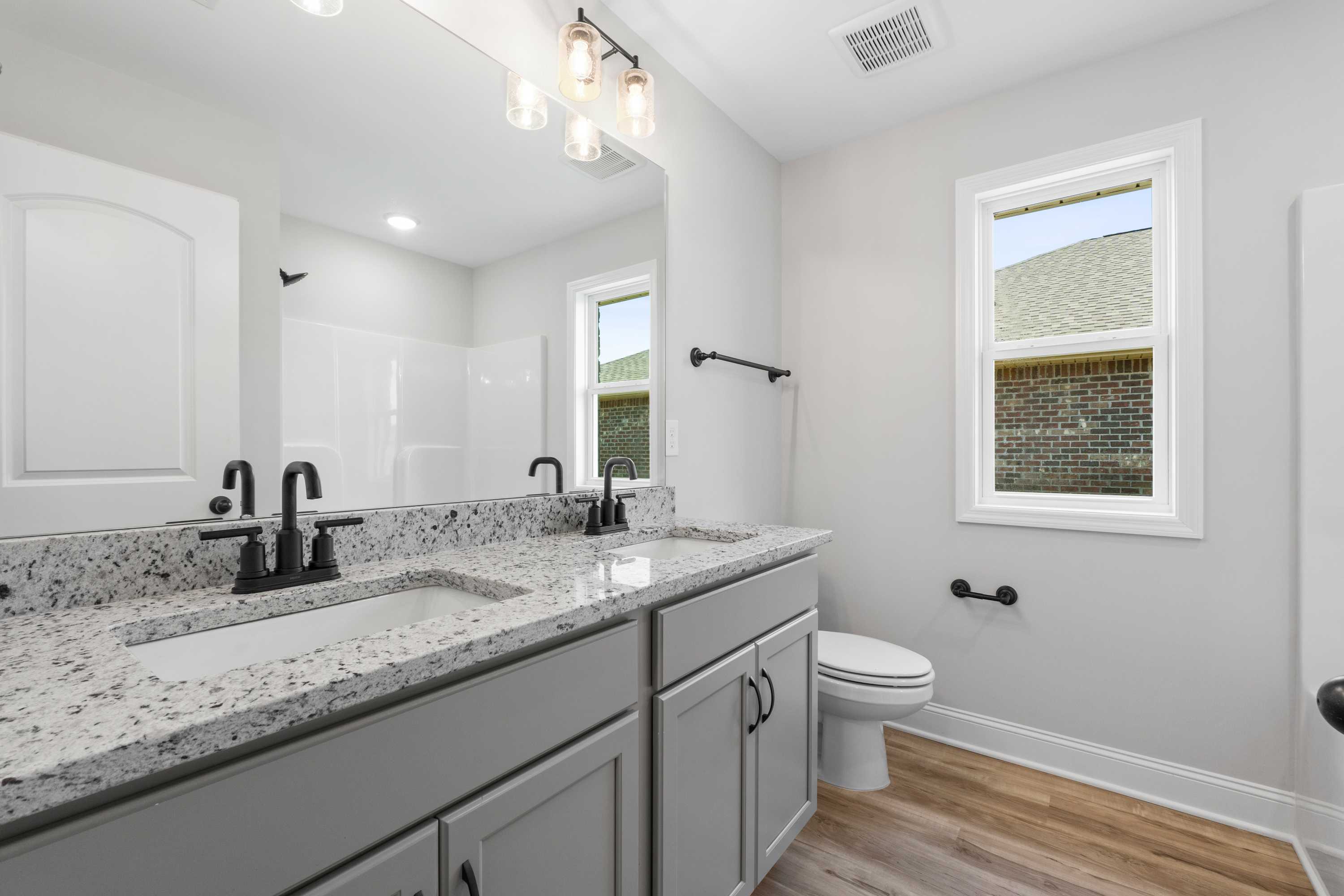 Spacious master bathroom in The Everett C with double vanity, quartz counters, gray cabinets, and large window