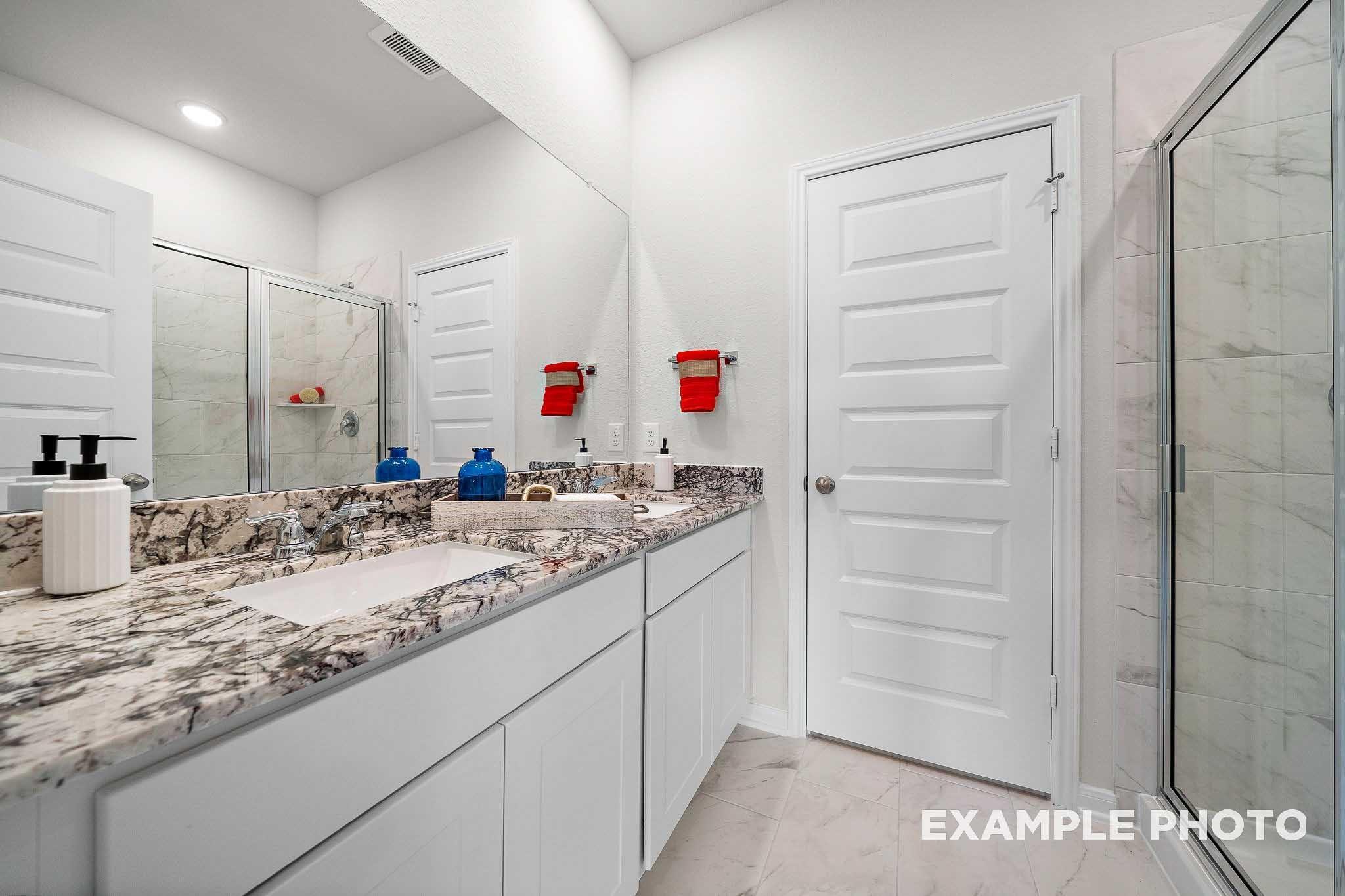 Luxurious master bathroom with double vanity, quartz counters, frameless glass shower in Davidson Homes San Marcos E, Conroe TX