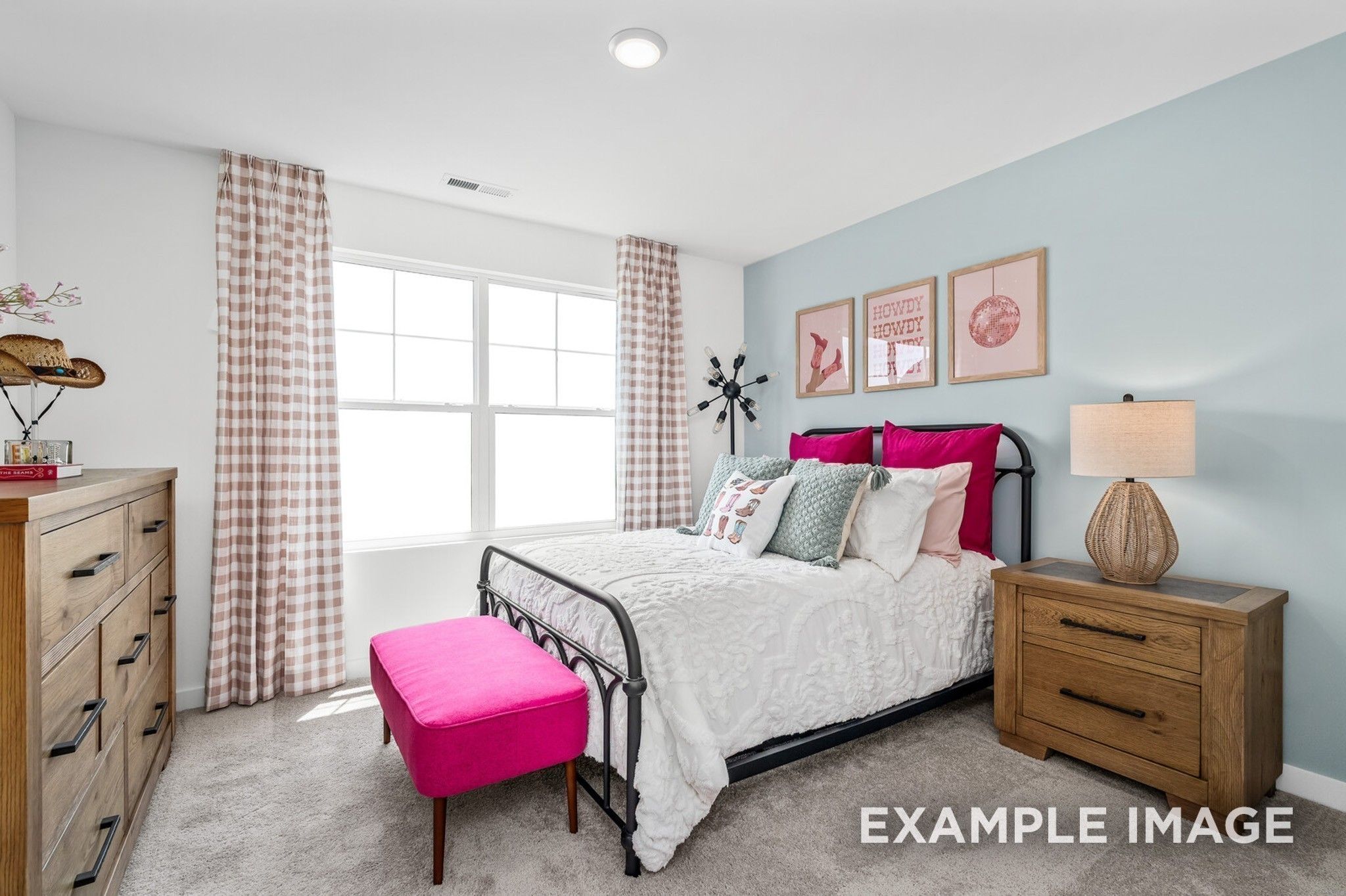 Cozy secondary bedroom with light blue walls, wrought iron bed, pink bench, wooden dresser, and large window in Davidson Homes The Ash A, Gallatin, TN