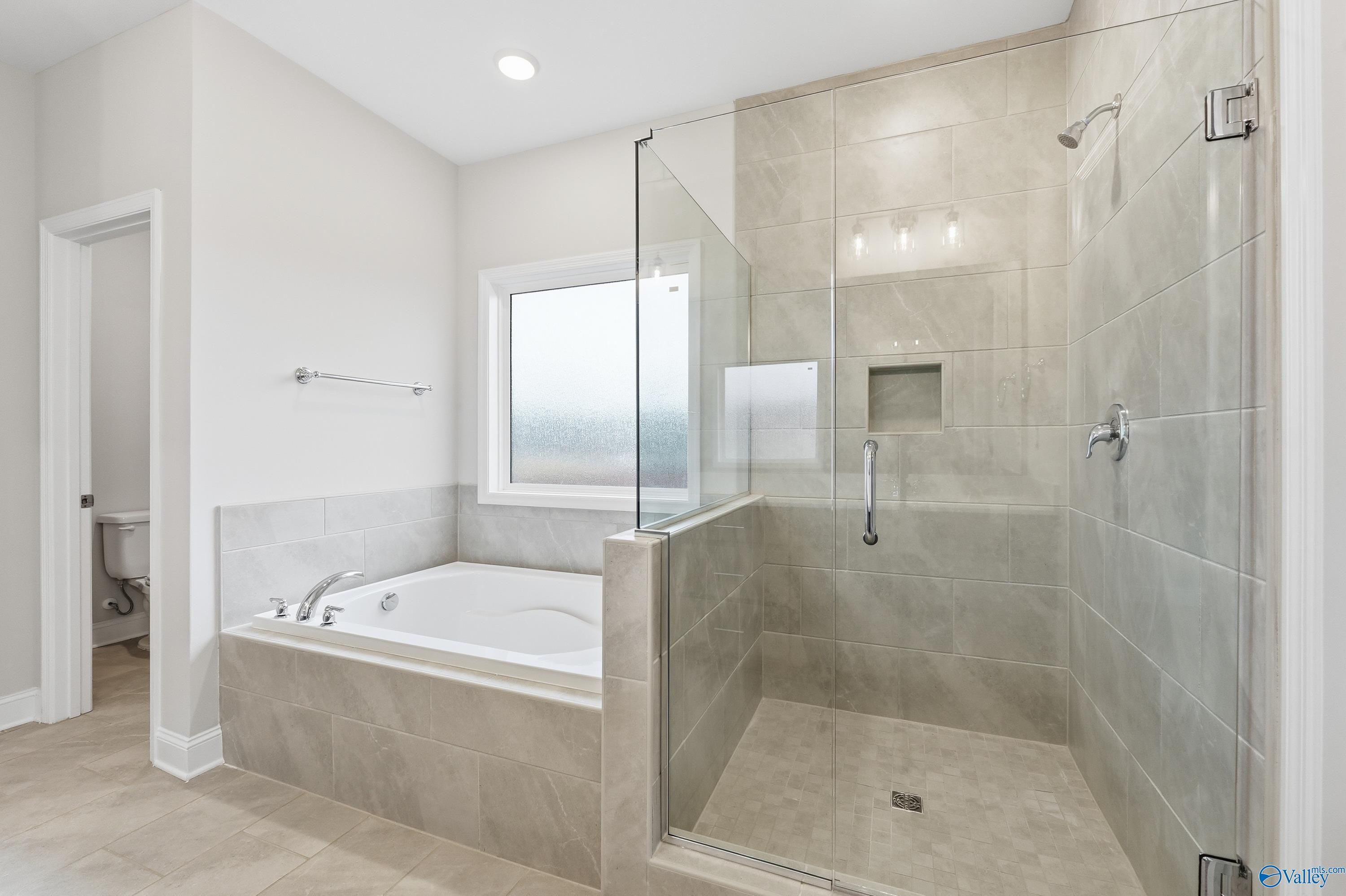 Luxurious master bathroom with freestanding soaking tub and glass shower in The Kirkland floor plan, Decatur, Alabama