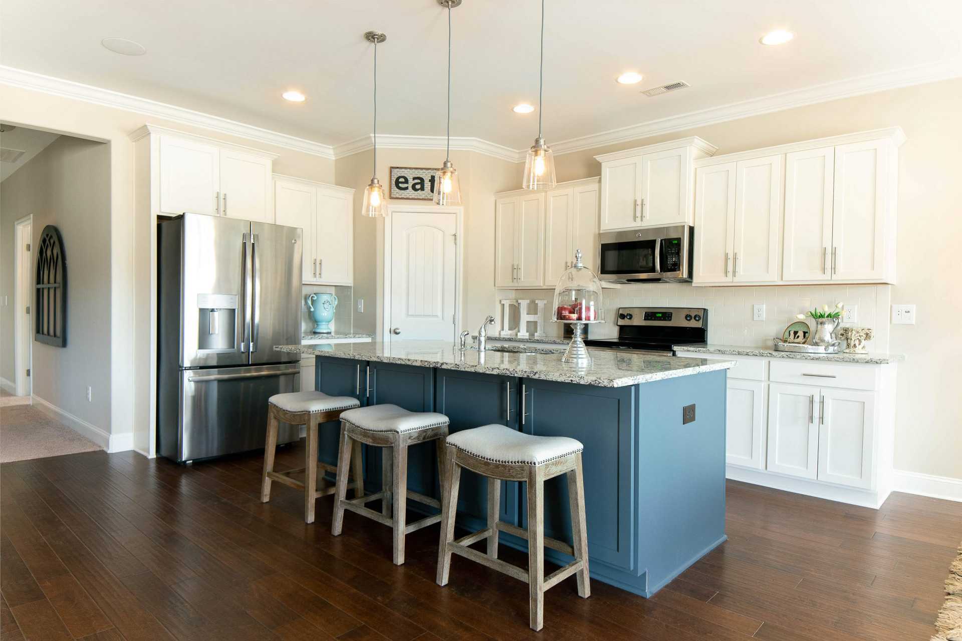 Spacious kitchen at The Dairy at Oak Grove in South Huntsville AL with white cabinets, navy island, stainless appliances, hardwood floors