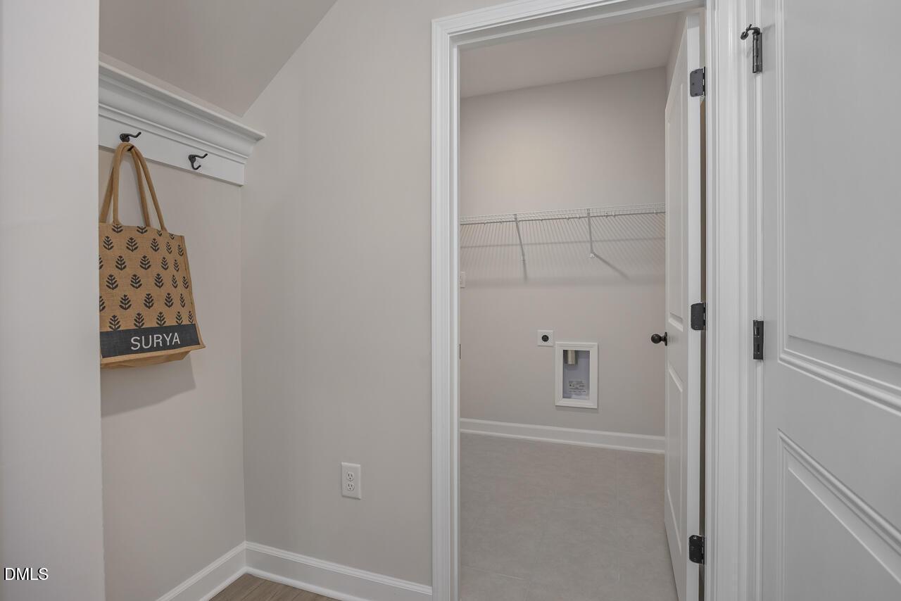 Spacious laundry room with hanging rods, utility sink, and beige walls in Davidson Homes The Ash B, Lillington, NC