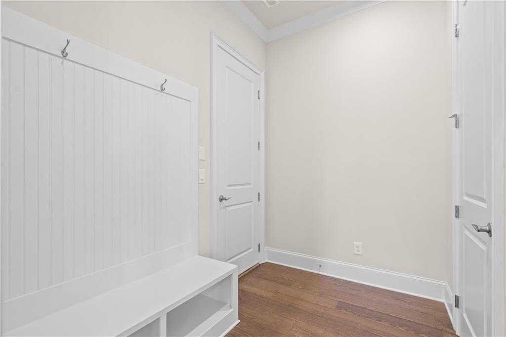 White beadboard mudroom with built-in bench, hooks, and hardwood floors in Davidson Homes Arlington A, East Cobb, Georgia