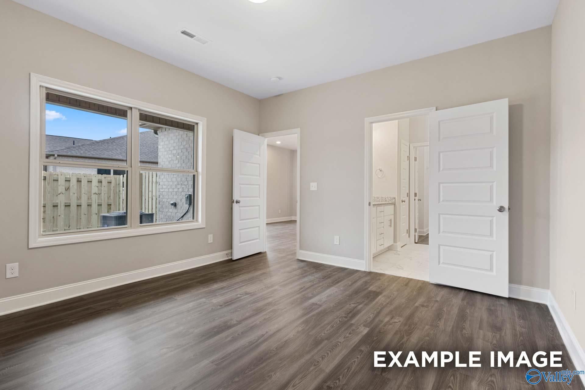 Bright master bedroom with large window, hardwood floors, and open en-suite bathroom in Davidson Homes The Camilla A, Hartselle, AL